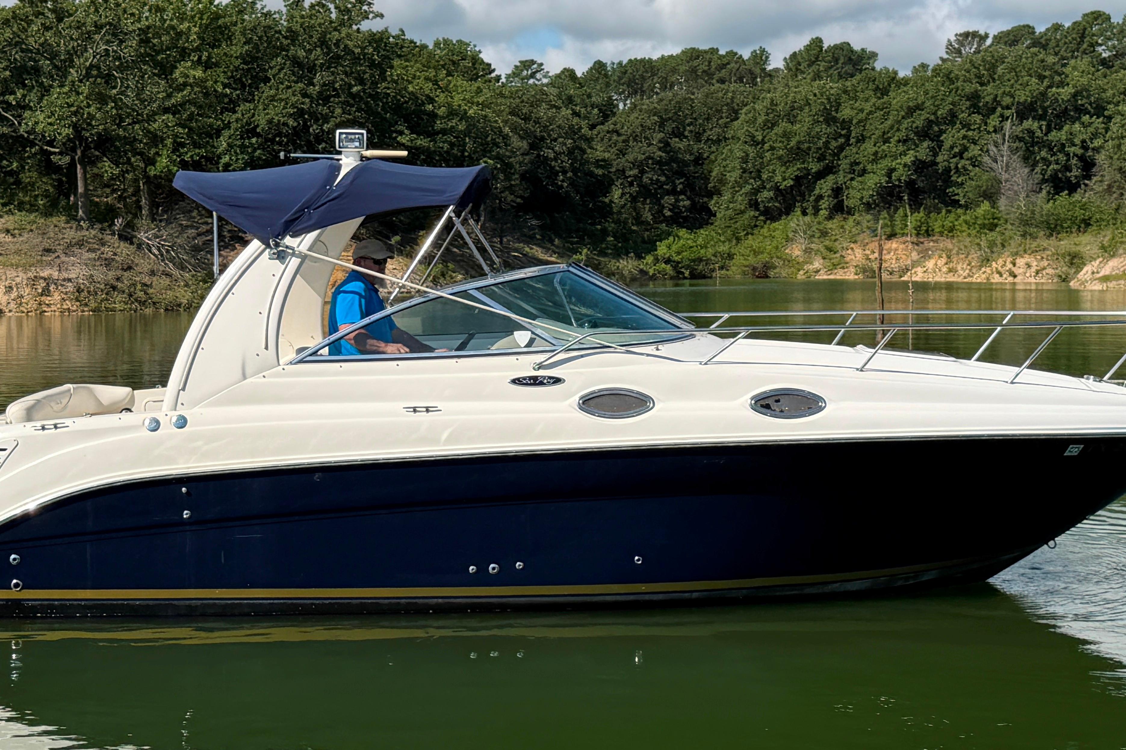 2004 Sea Ray Sundancer 260 boat cruising on a calm lake with lush green surroundings.