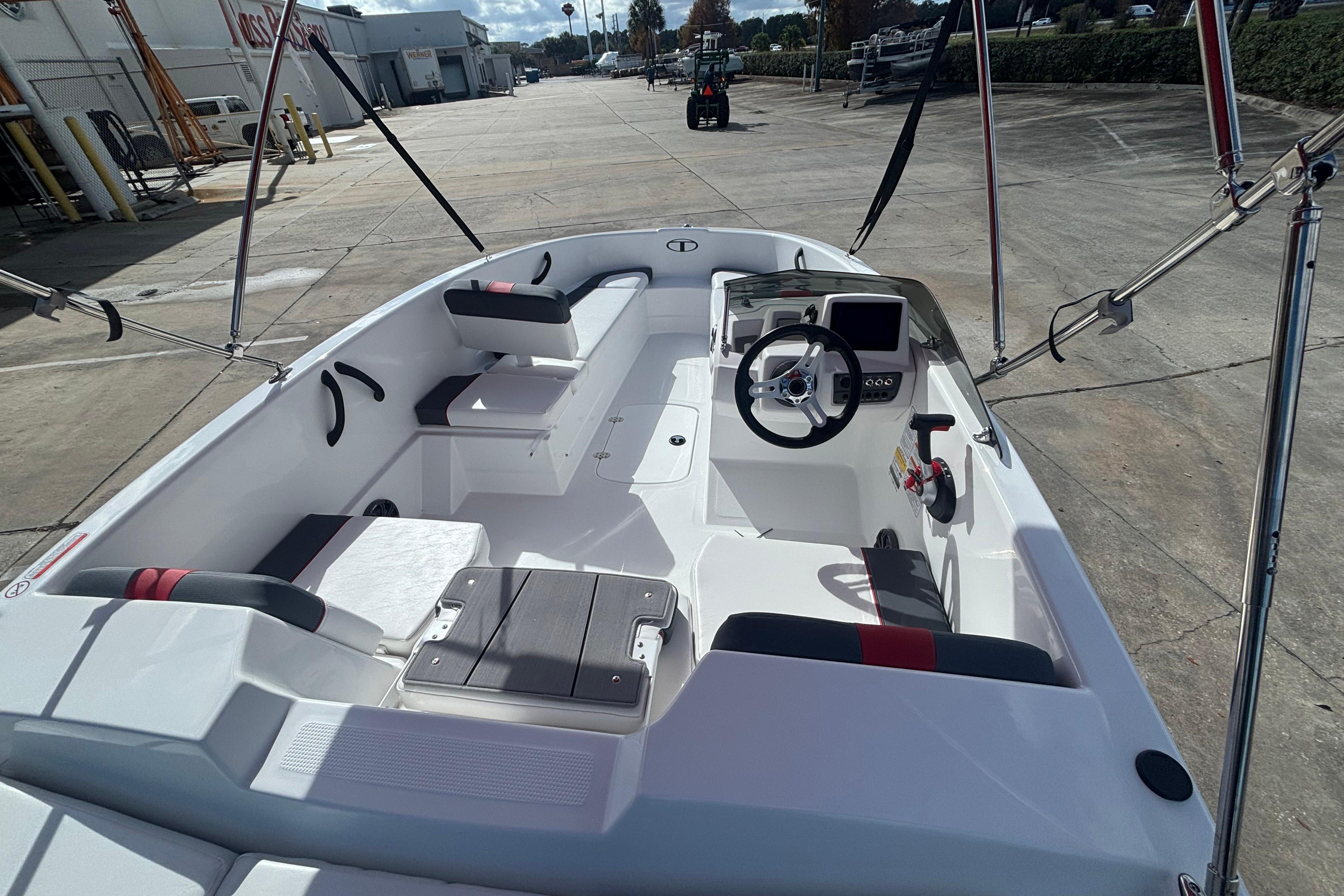 2026 Tahoe T16 boat interior with steering wheel and seating, parked outdoors.