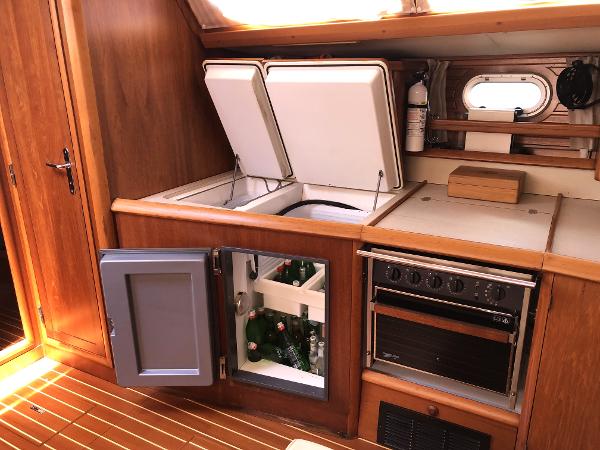 Interior of 2001 Jeanneau 45.2 yacht kitchen with fridge, stove, and wooden cabinetry.