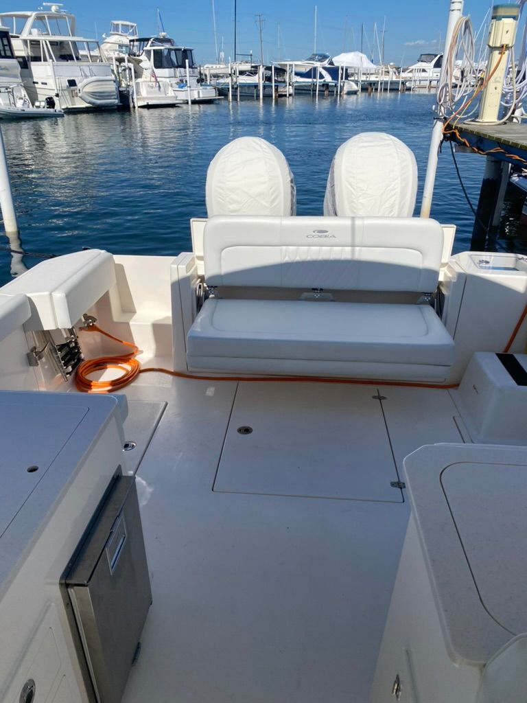 2023 Cobia 330 boat at dock with seating area.