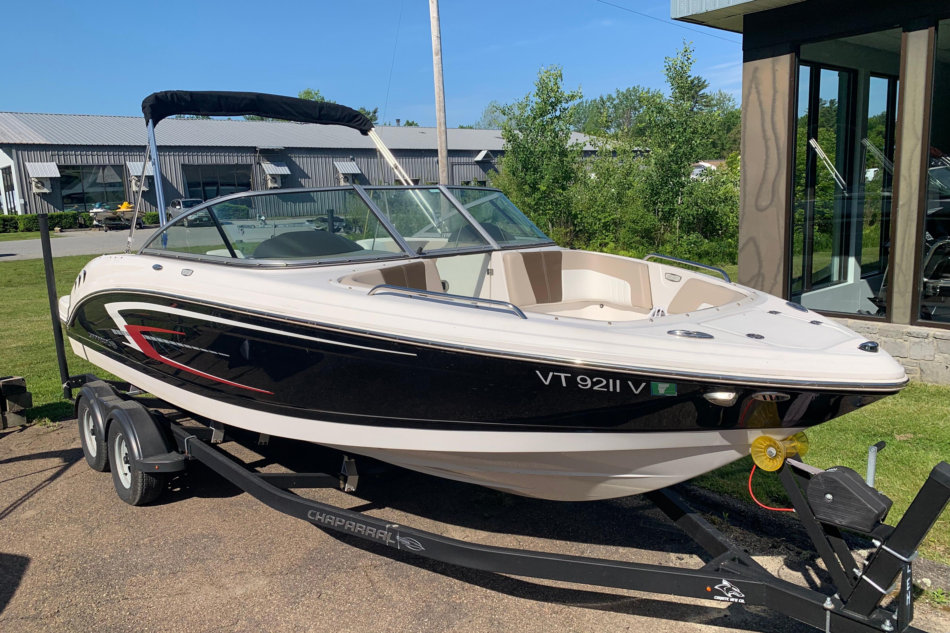 2022 Chaparral 23 SSi boat on trailer, black and white design, parked outdoors.