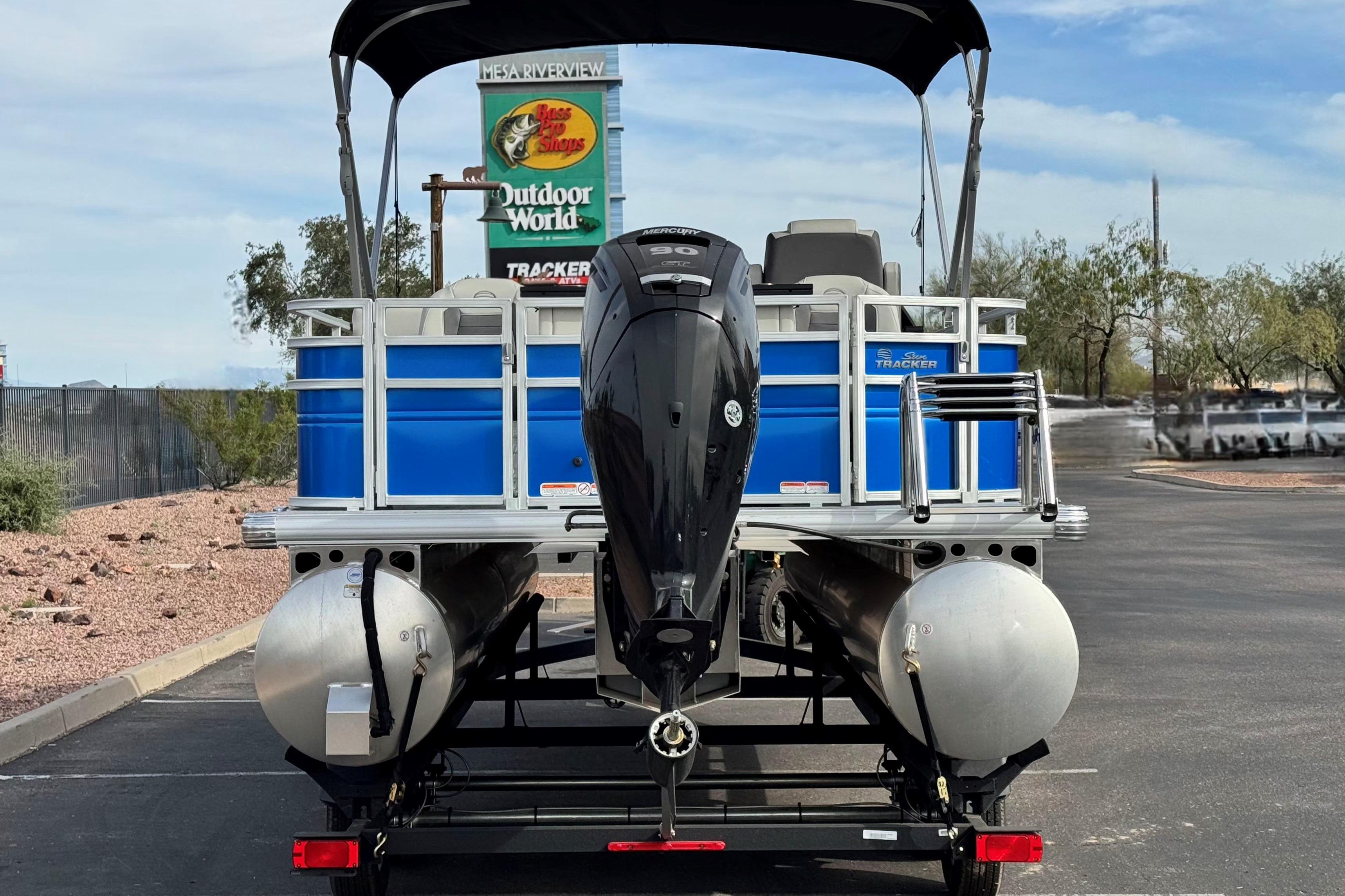 2026 Sun Tracker Fishin' Barge 20 DLX pontoon boat with outboard motor in parking lot.