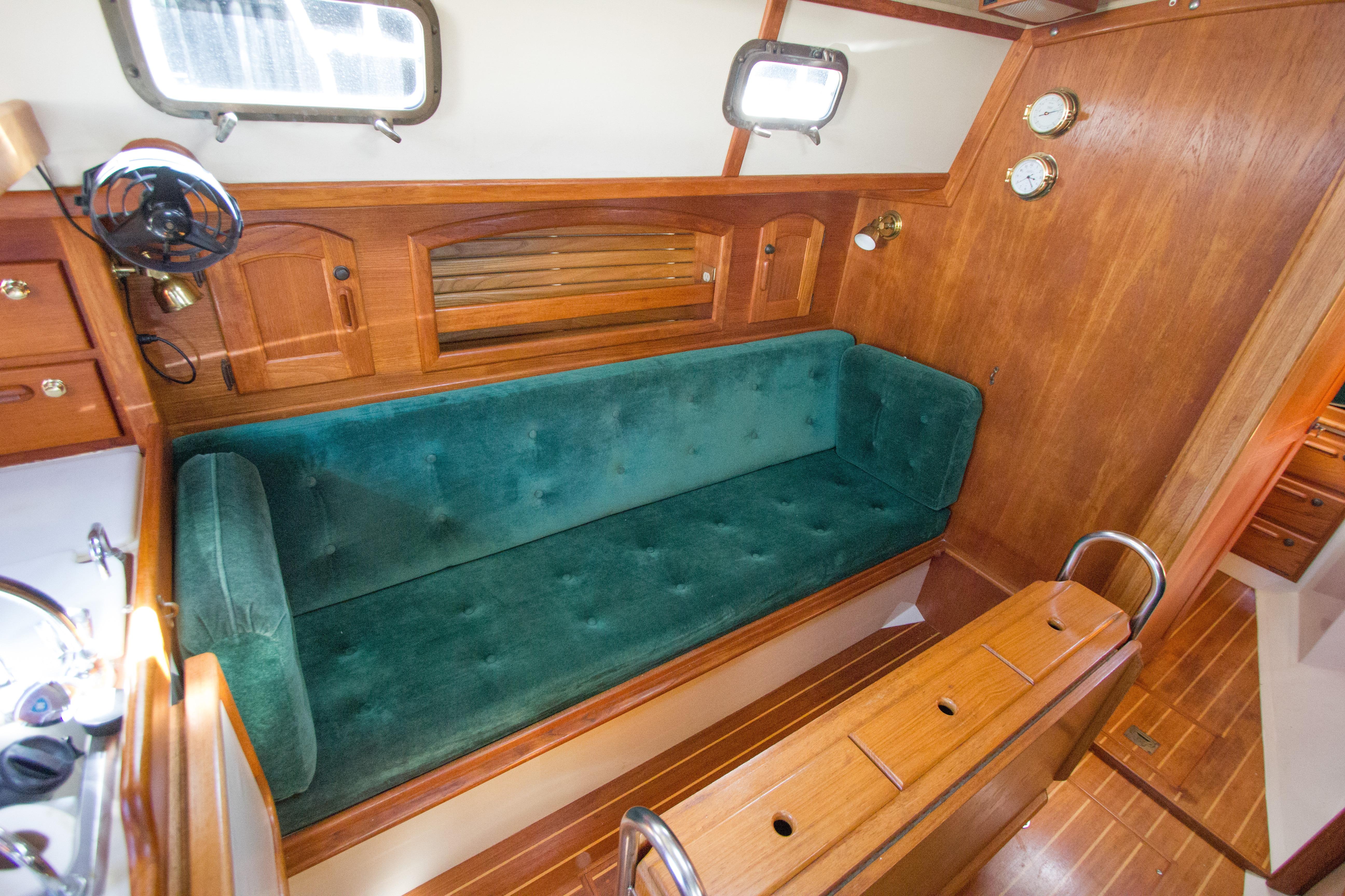 Cozy interior of 1992 Pacific Seacraft 34 sailboat with green sofa and wooden accents.