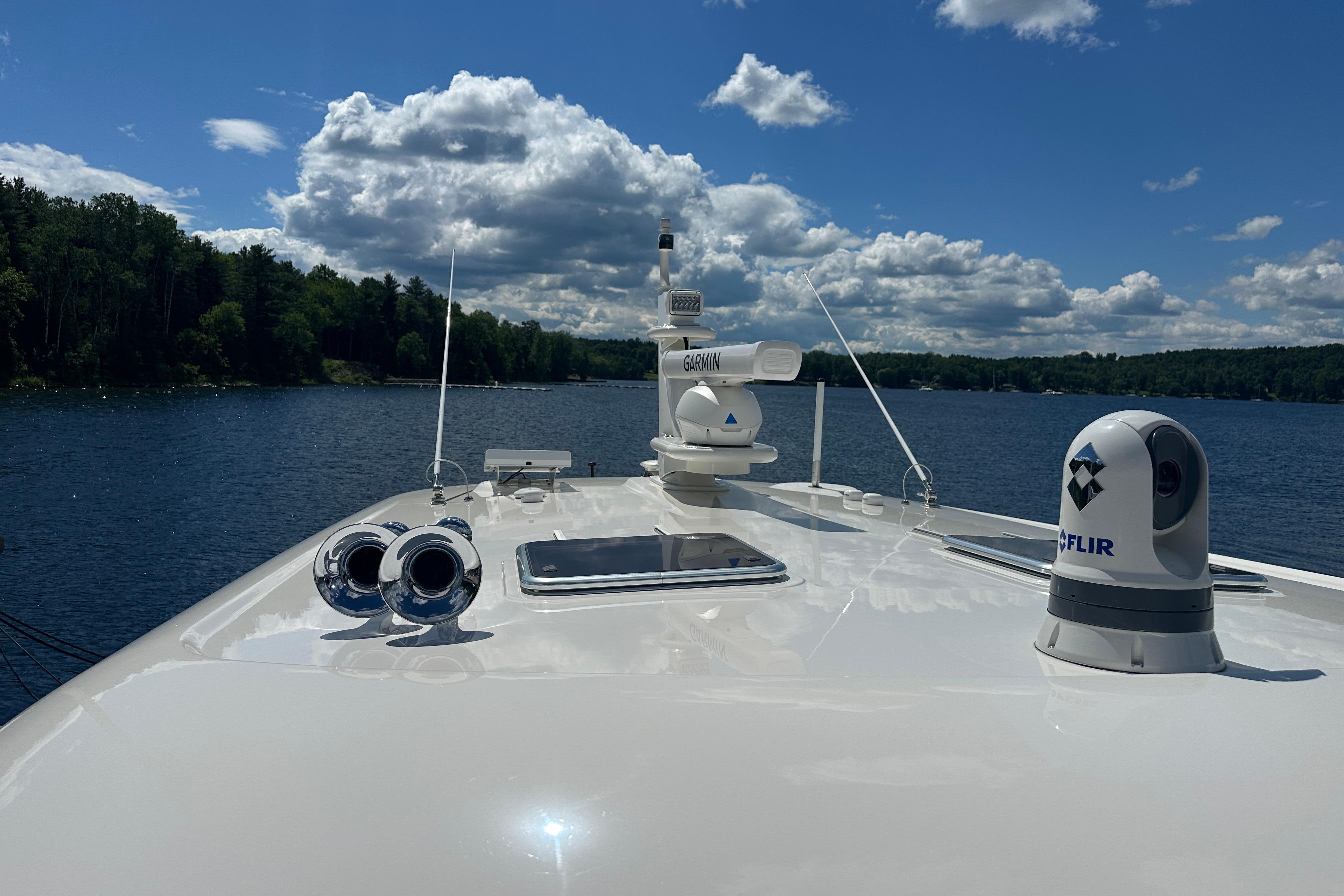 2025 Sabre 48 Salon Express yacht on a serene lake under a partly cloudy sky.