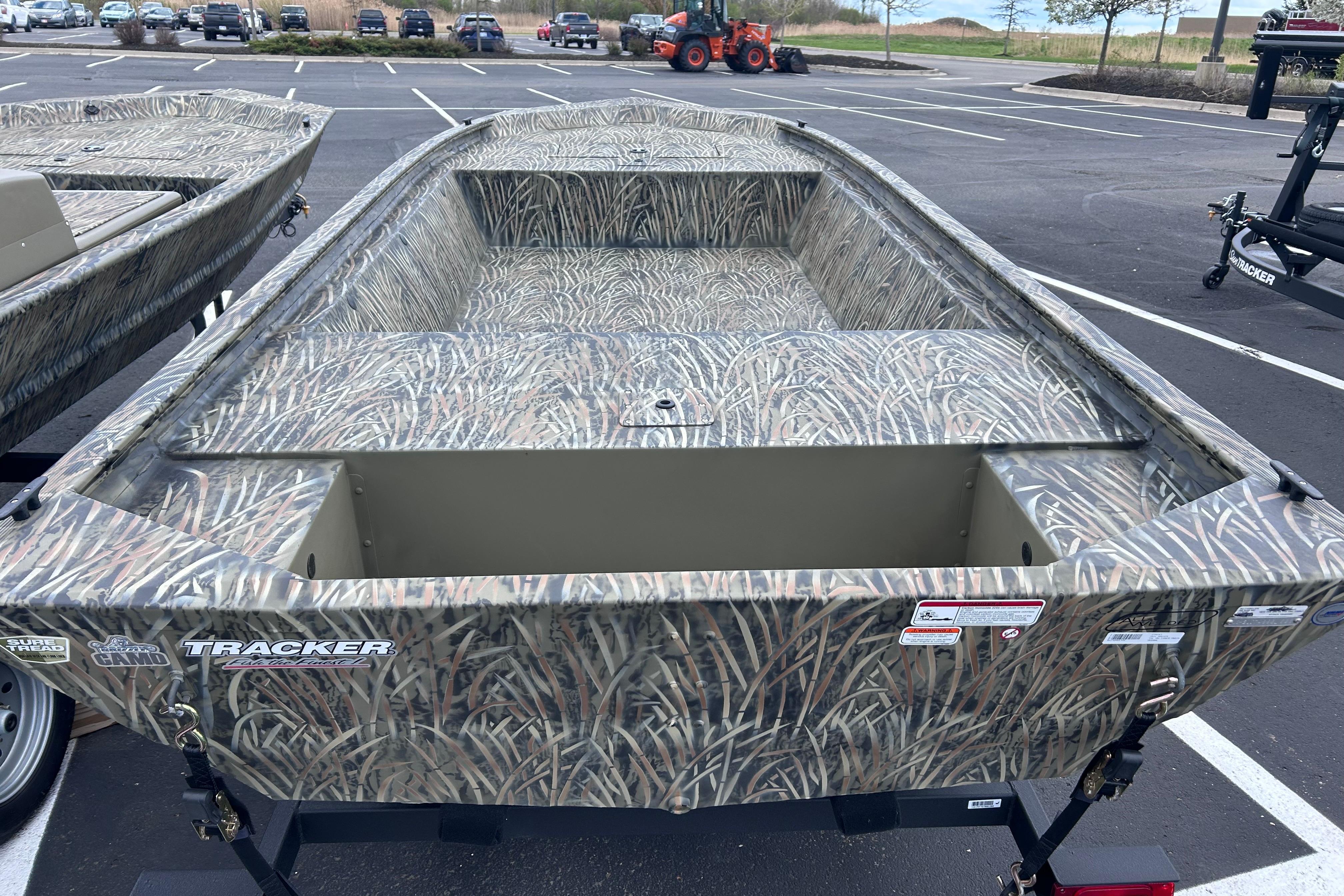 2026 Tracker Grizzly 1648 Utility boat with camouflage design in a parking lot.