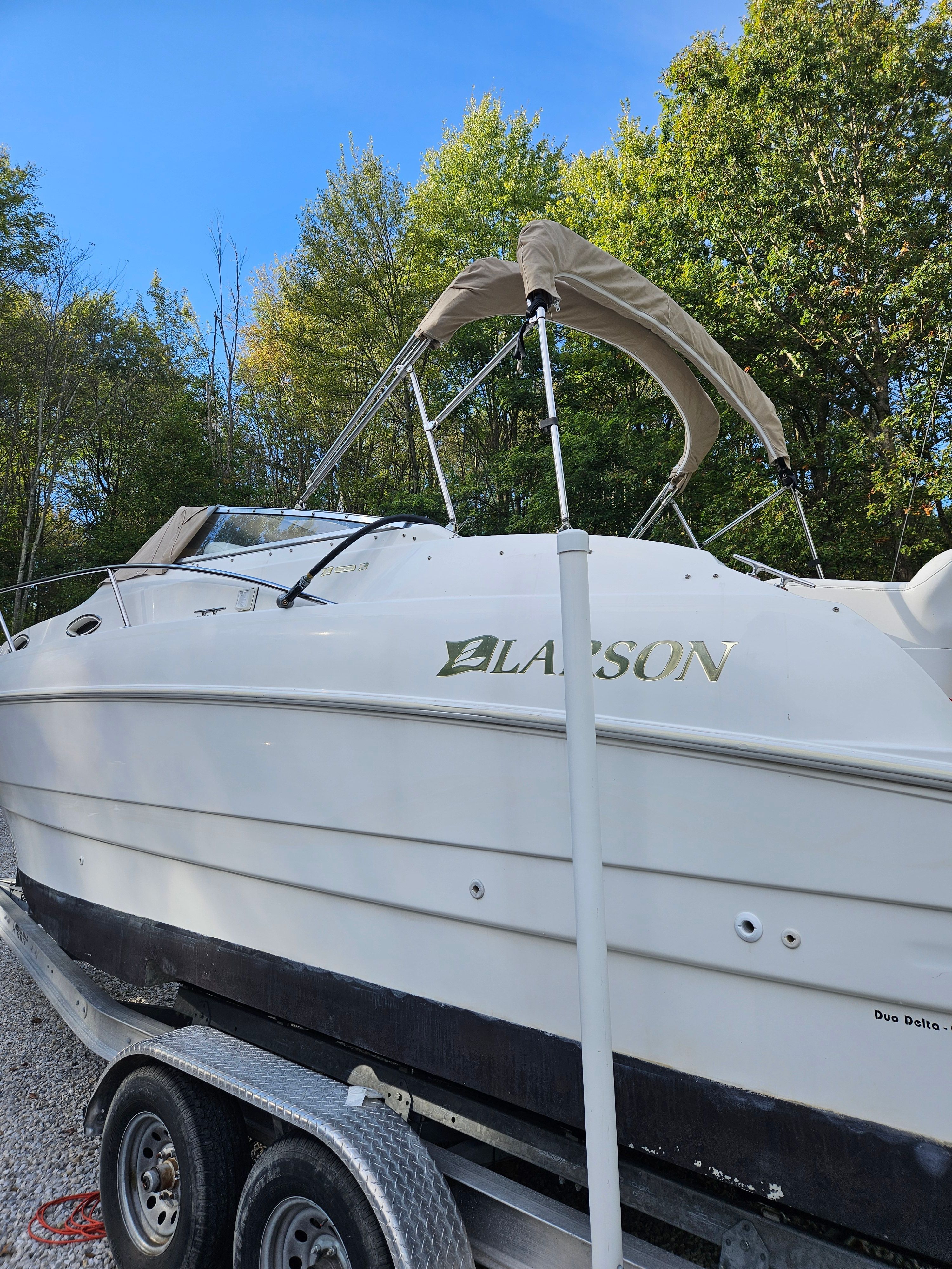 1998 Larson Cabrio 254 boat on trailer outdoors.