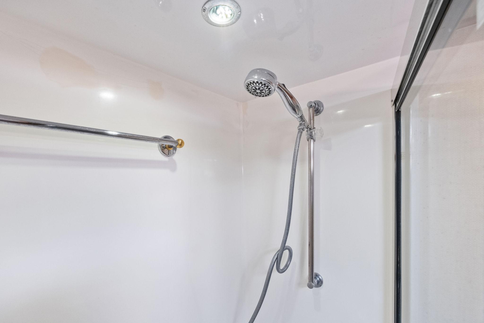 Shower area in 1998 Hatteras 60 Convertible yacht, featuring chrome fixtures and glass door.