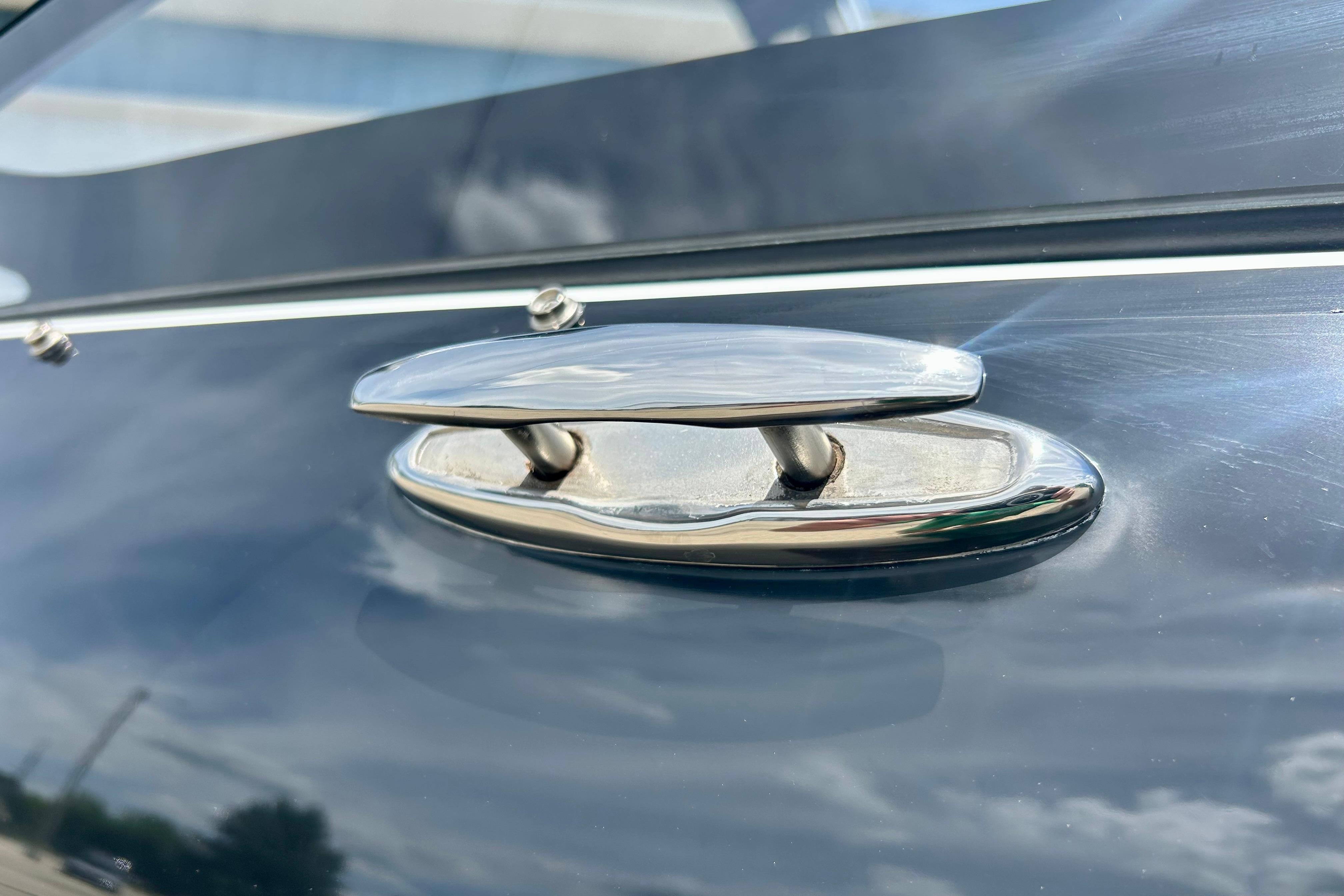 Chrome cleat on 2021 Scarab 195 ID boat, reflecting sky and clouds.