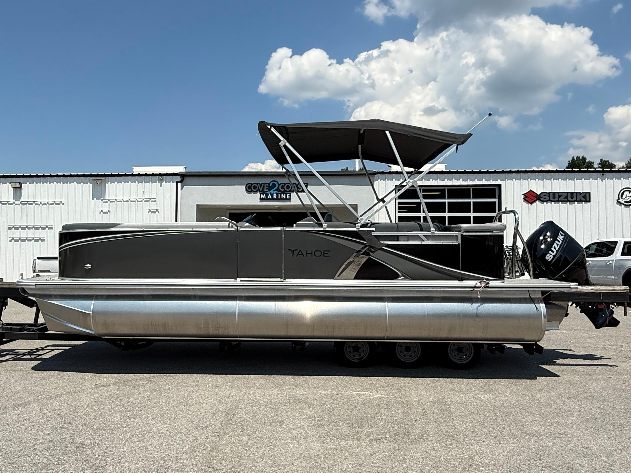 2025 Tahoe Pontoon LTZ Cruise boat with canopy, parked outside marine dealership.