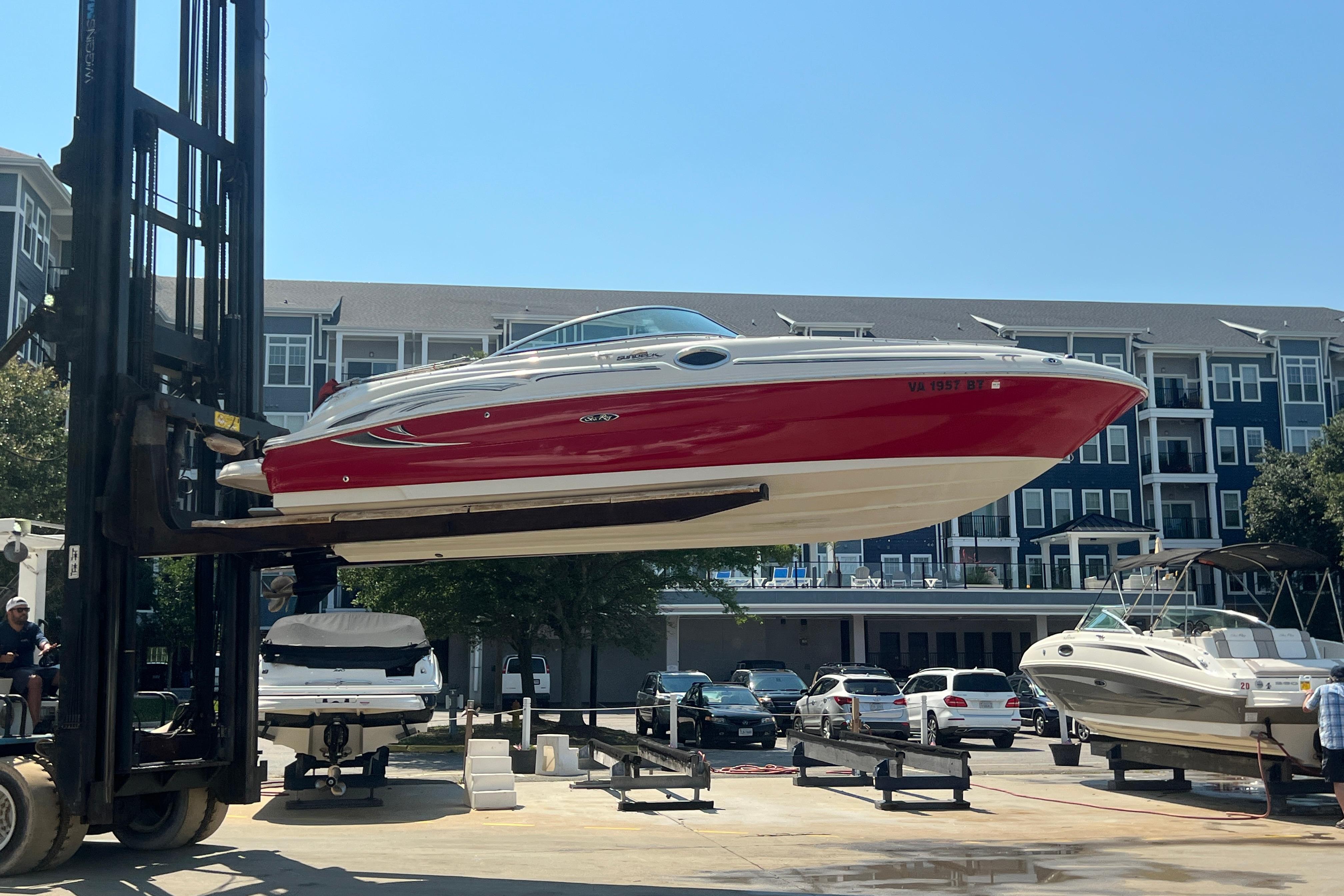 2005 Sea Ray 240 Sundeck boat lifted by forklift in marina setting.