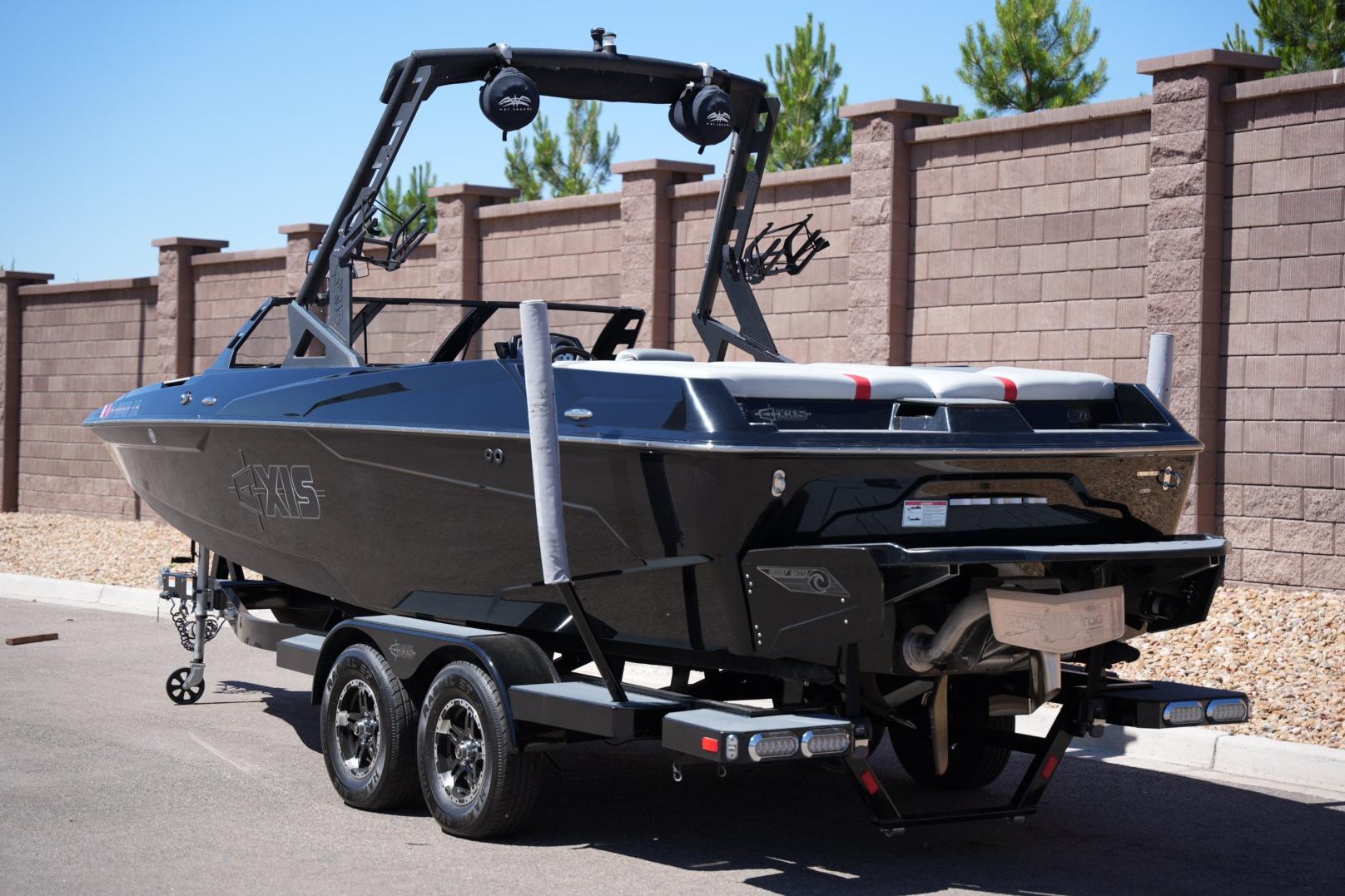 2019 Axis A22 boat on trailer, sleek black design, parked near brick wall.