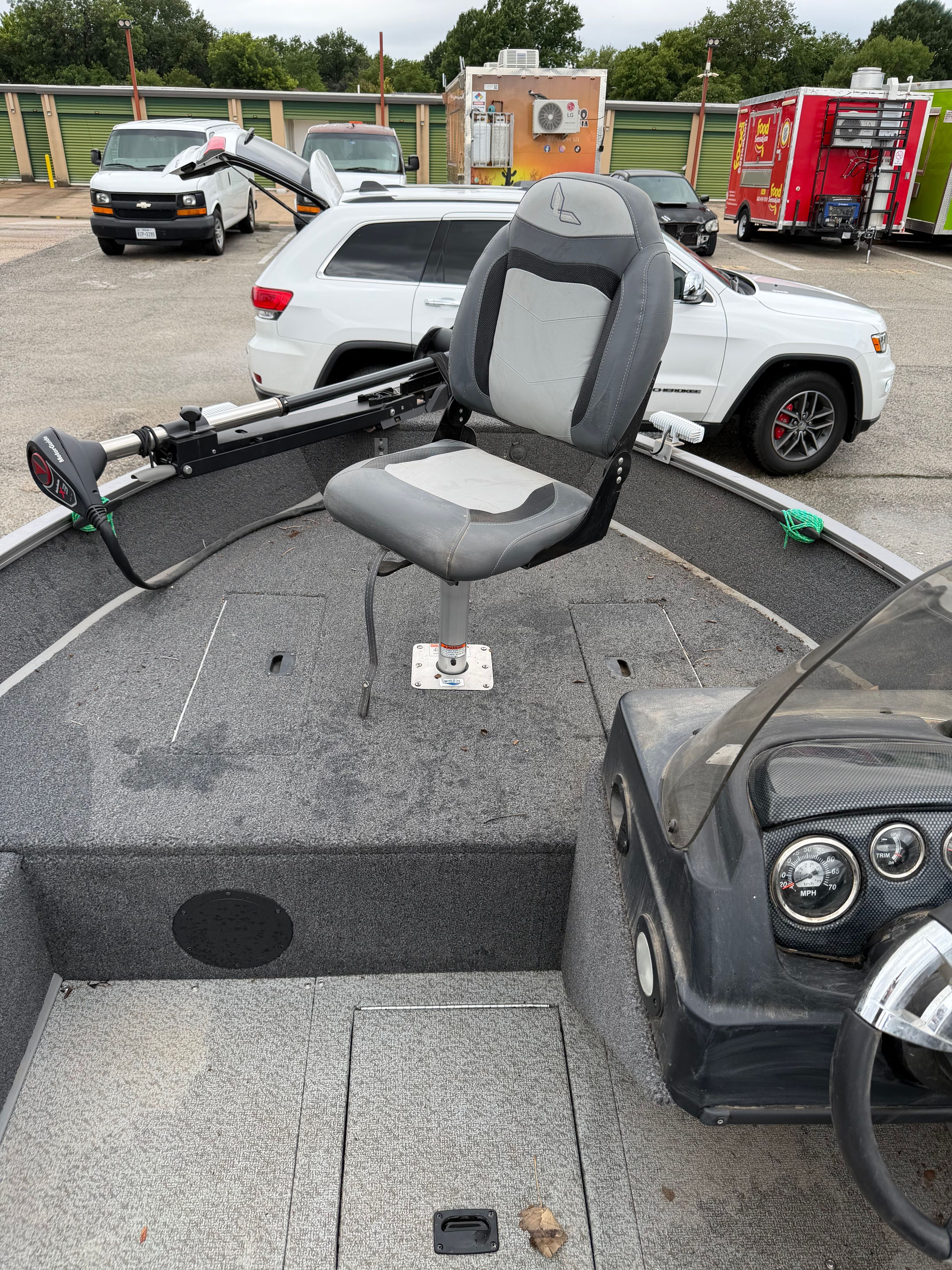 A fishing boat with a gray seat and console, parked in a lot.