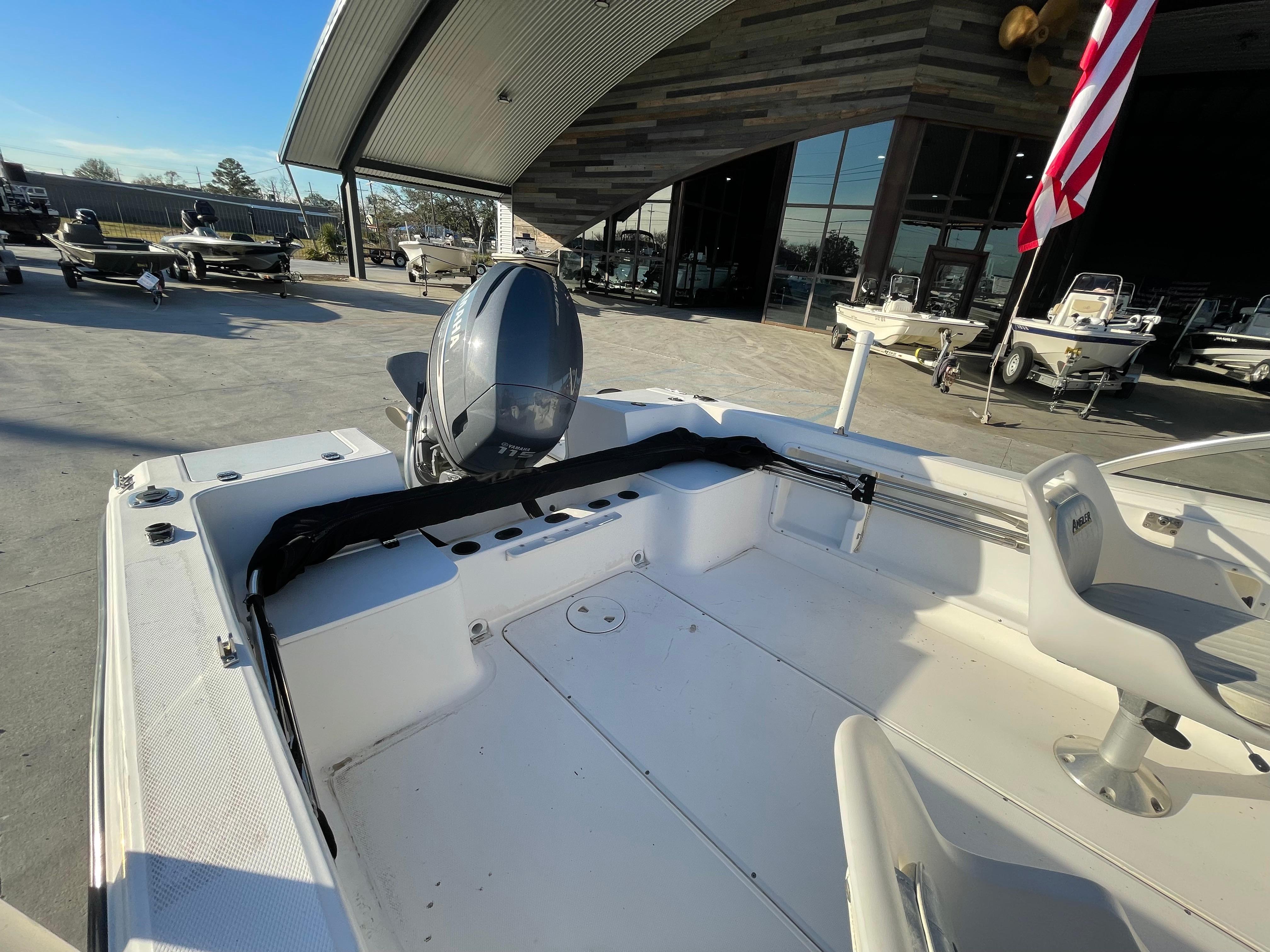 2002 Angler 18 DC boat with outboard motor, displayed outdoors near a showroom.