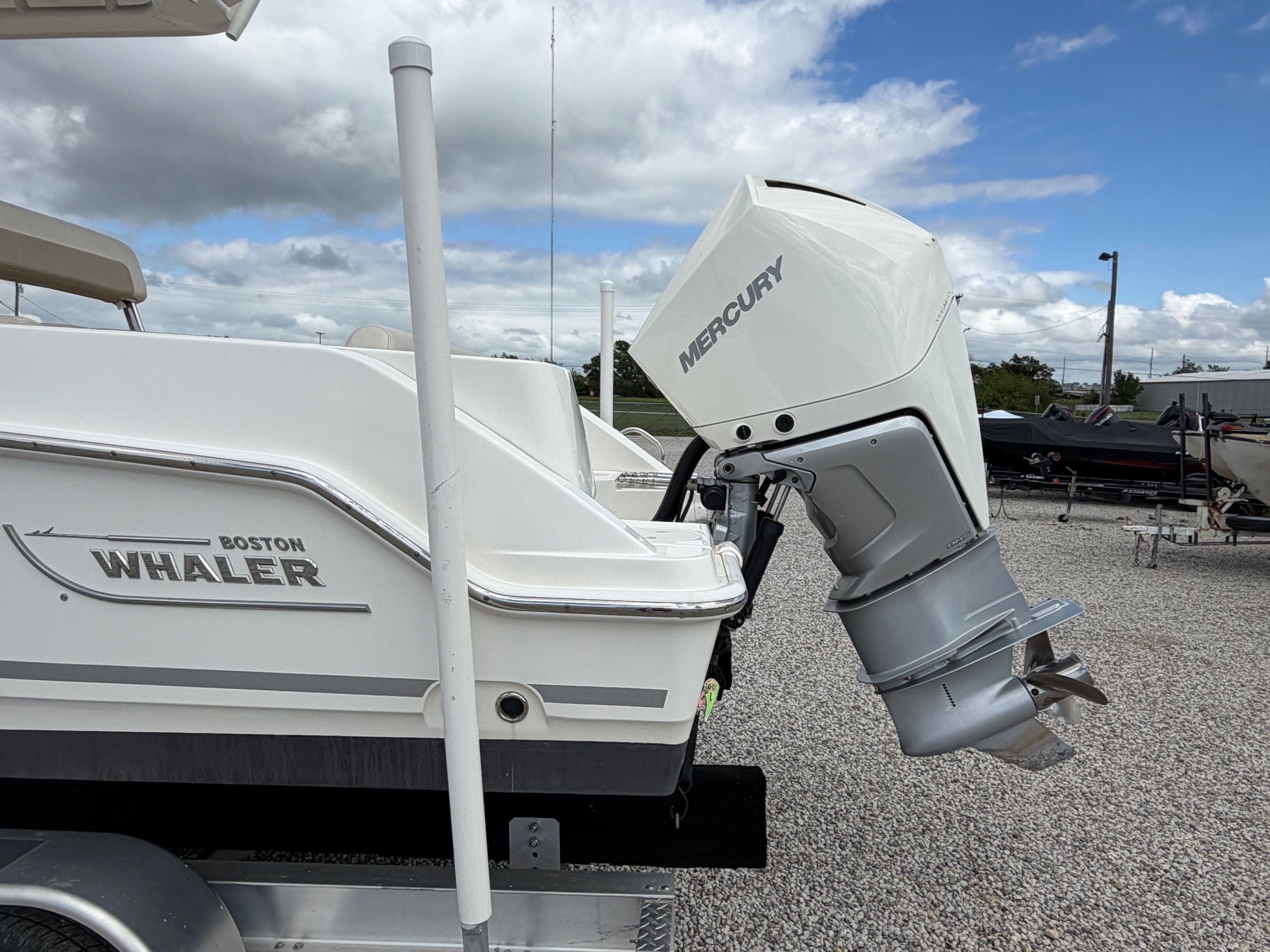 Boston Whaler 230 Outrage 2020 with Mercury engine on gravel lot.