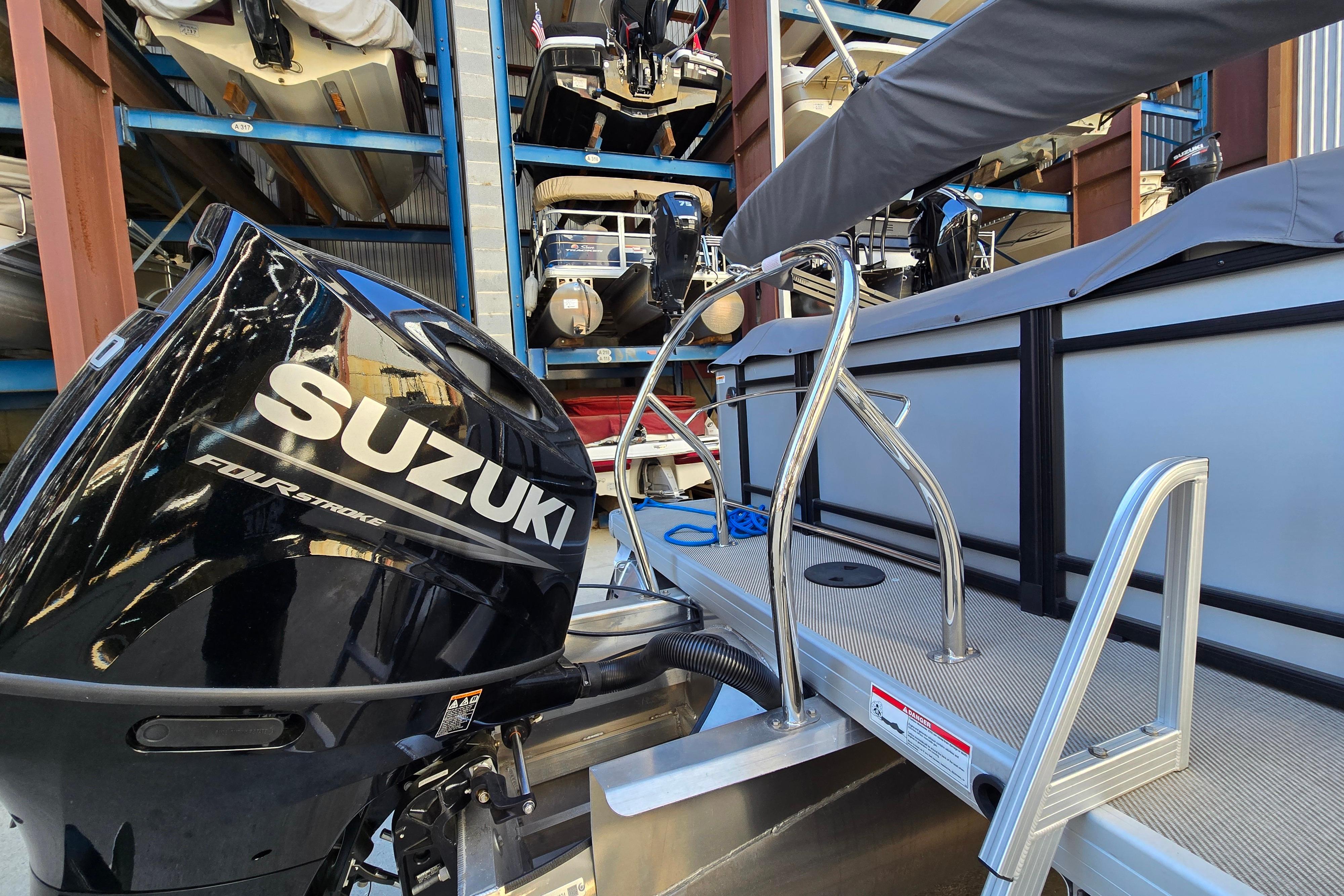2024 Godfrey Sweetwater 2486 SB with Suzuki four-stroke engine in storage facility.
