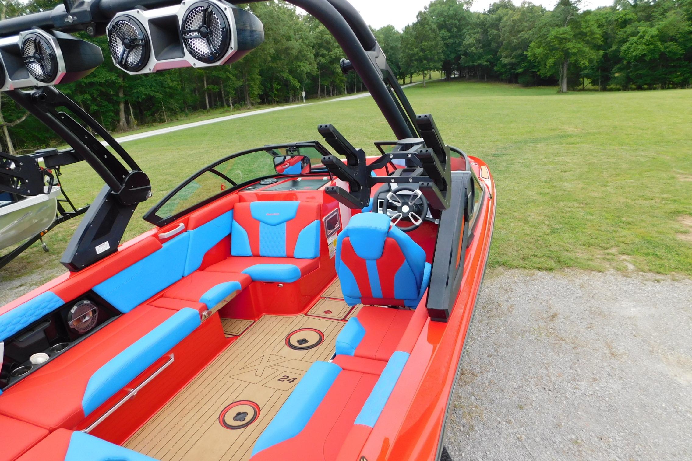 2022 MasterCraft NXT24 boat with vibrant red and blue interior, parked on grassy area.
