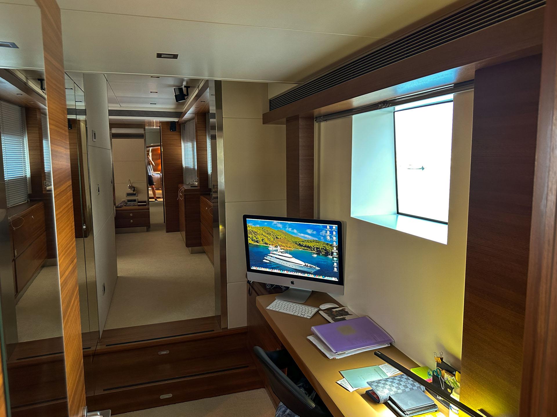 Luxurious yacht interior with a modern office space, featuring a computer and wooden accents.