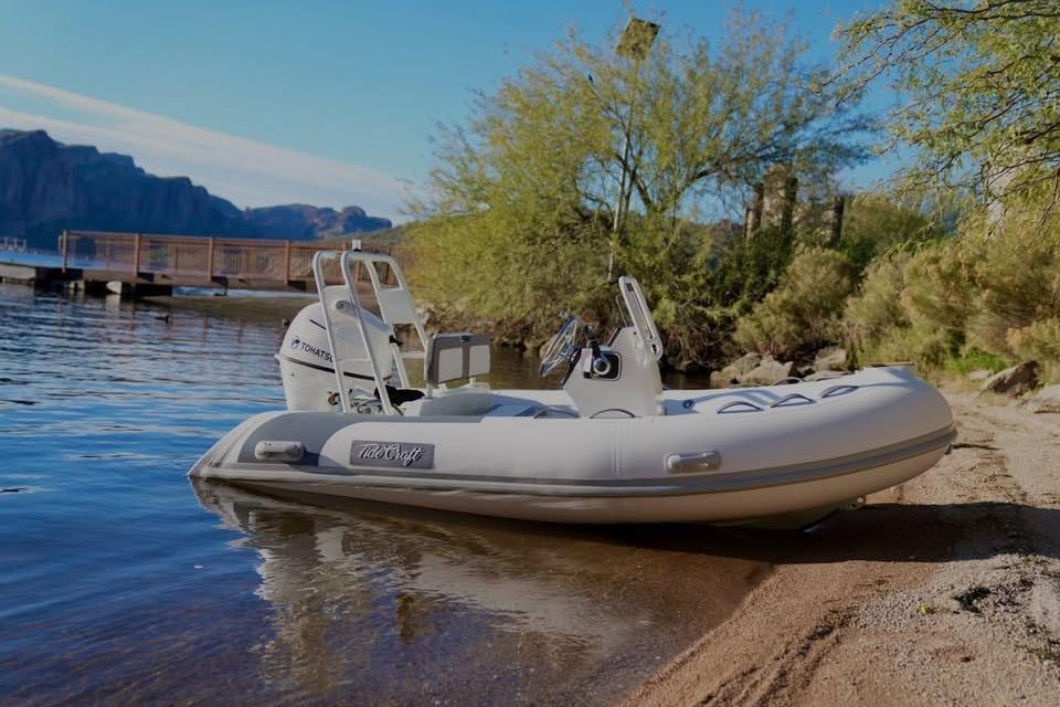 Tide Craft San Juan 11 boat, 2027 model, docked on a serene lakeside beach.