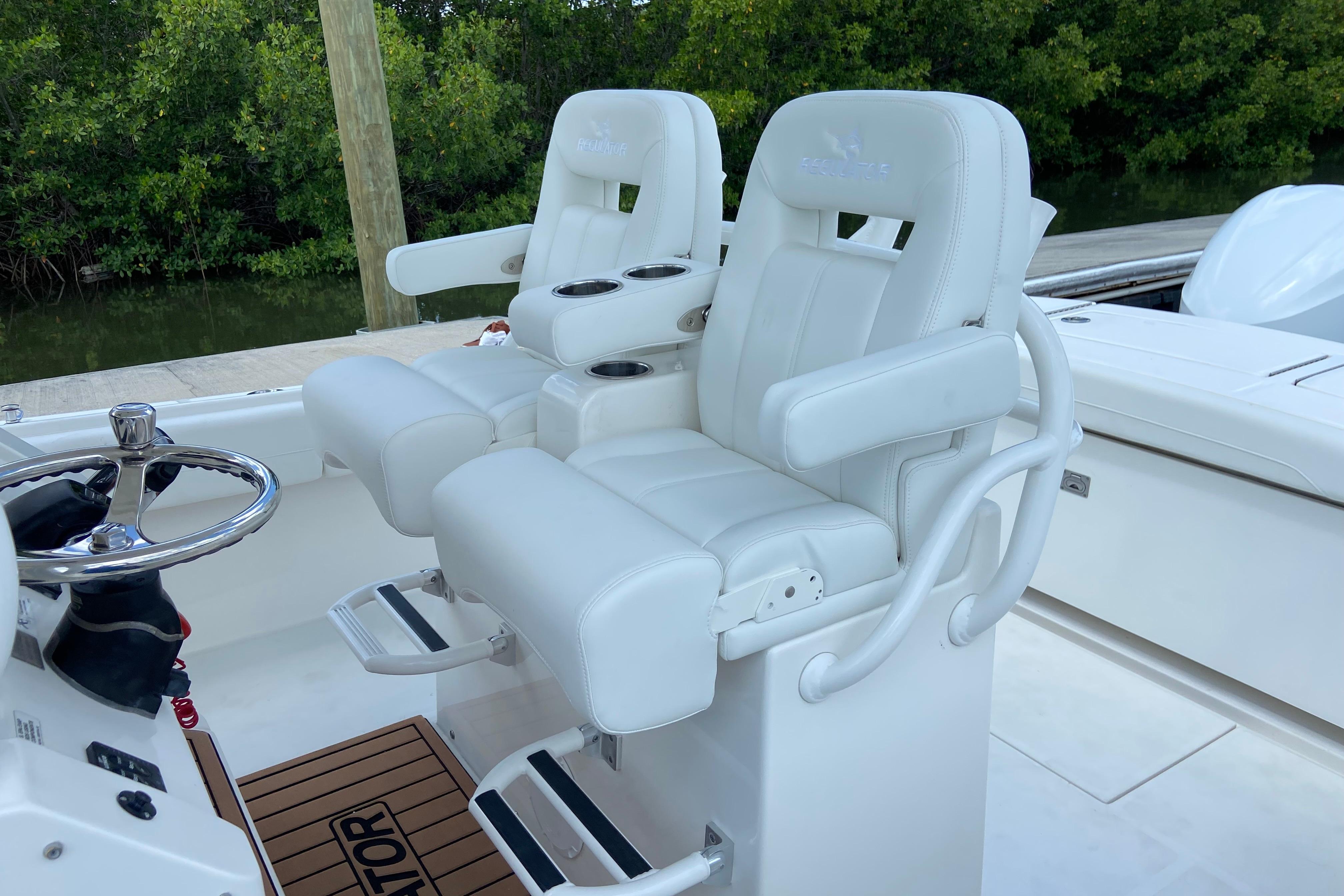 2021 Regulator 28 boat with white cushioned helm seats and steering wheel.
