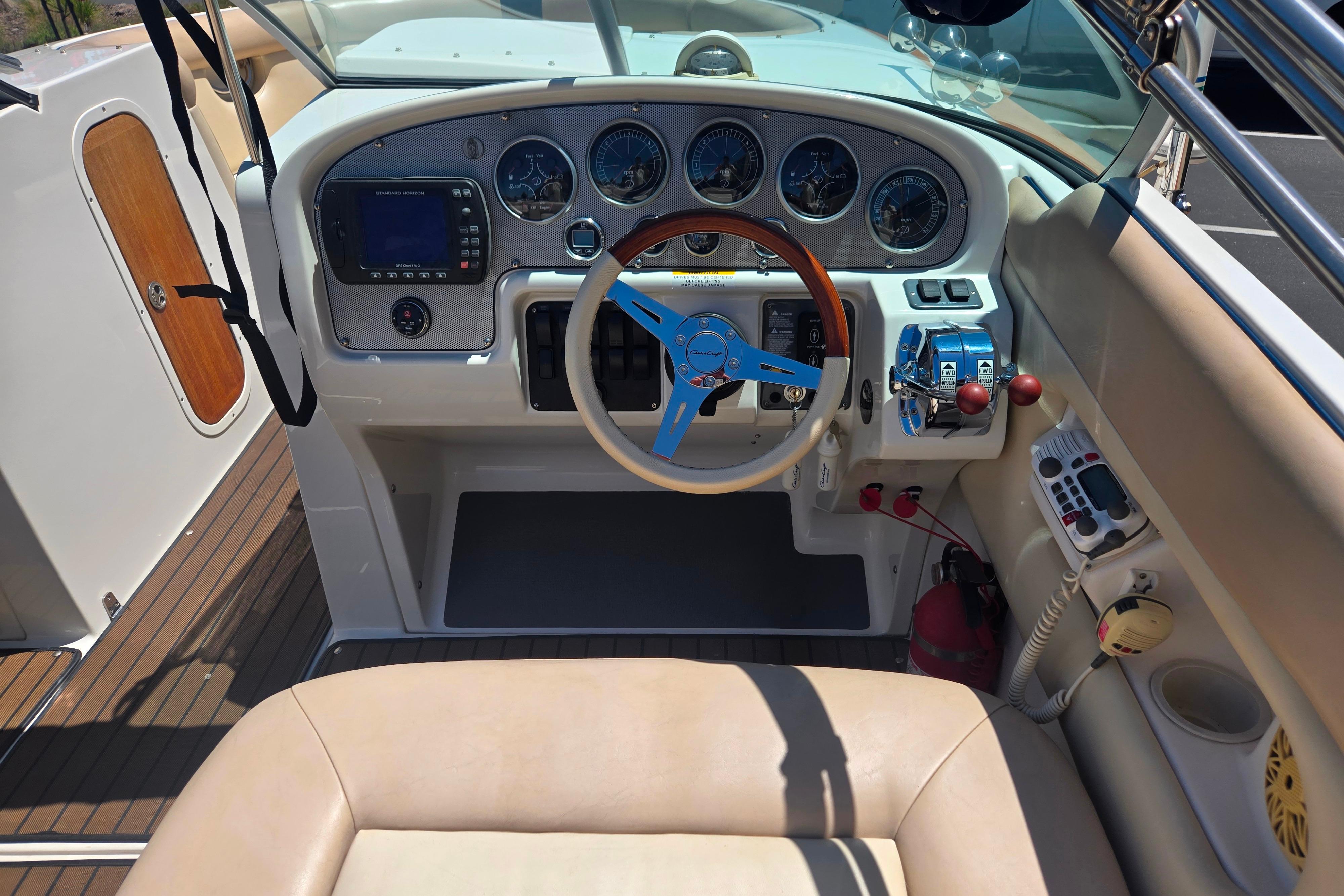 Interior view of 2002 Chris-Craft Launch 28 GT I/O boat cockpit with steering wheel and controls.