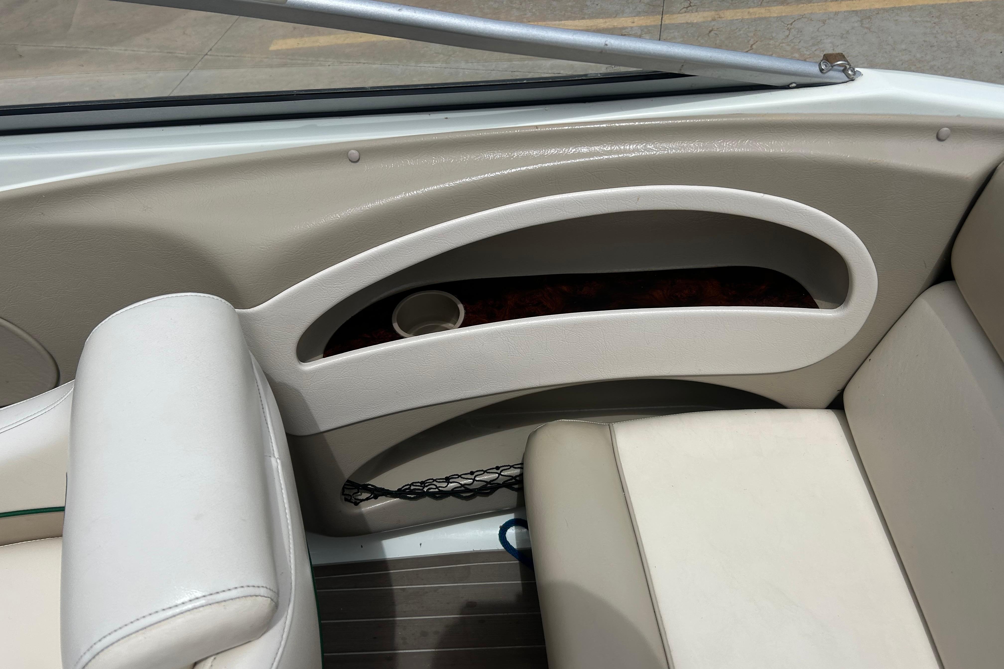 Interior of a 2000 Starcraft 1810 boat, featuring beige seating and storage compartment.