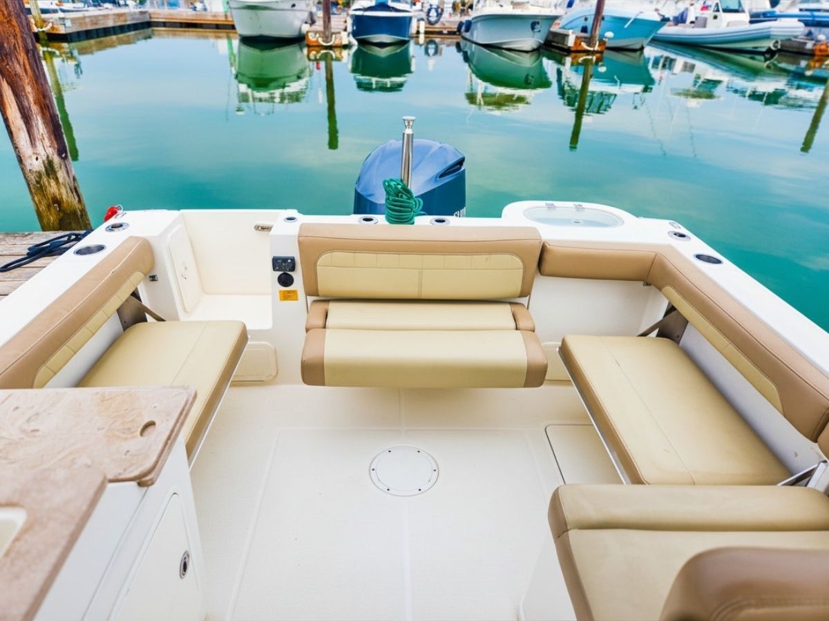 The image shows the cockpit of a 2020 Sailfish 245 DC with beige seating at a marina.