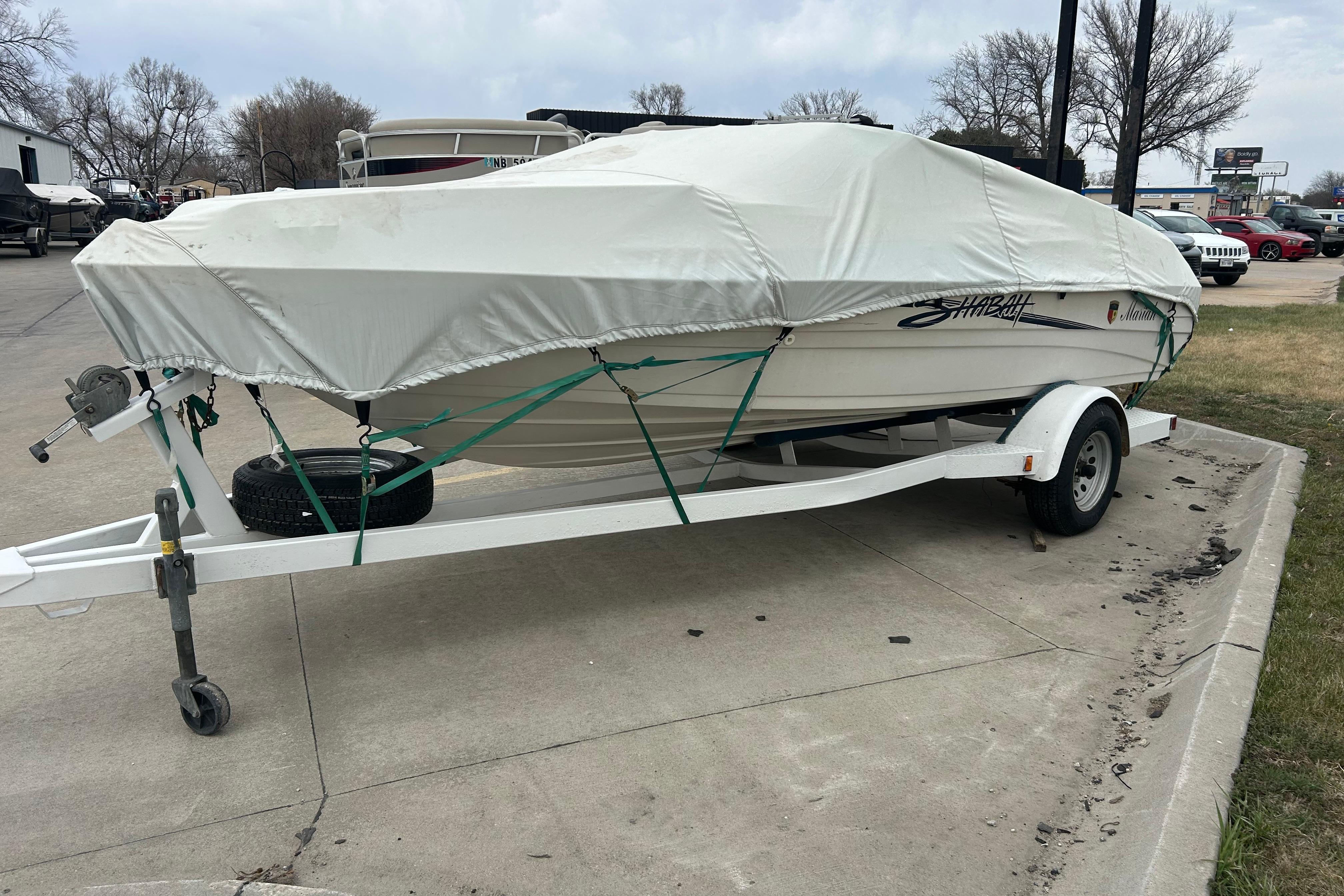 Covered 1996 Mariah 180 Shabah boat on trailer, parked on concrete surface.