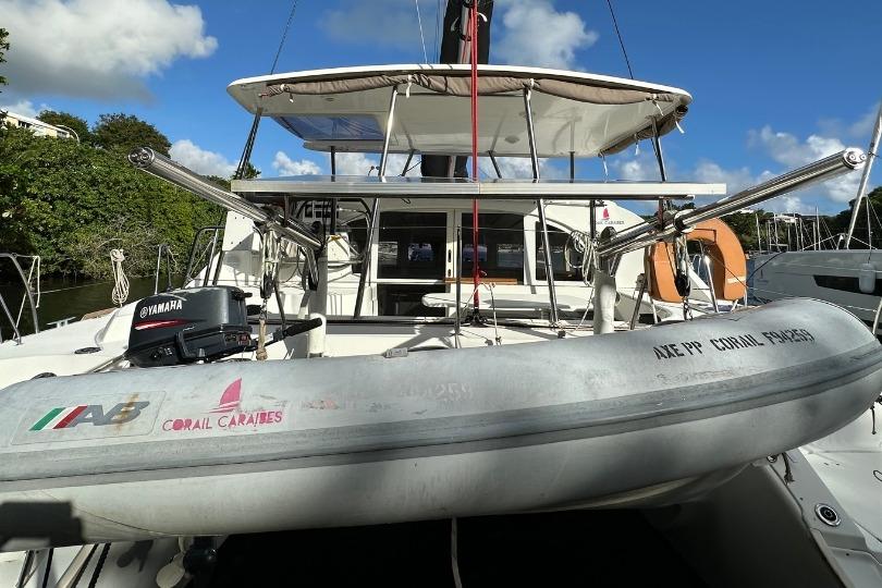 2018 Lagoon 380 catamaran with dinghy and Yamaha motor, docked under clear blue sky.