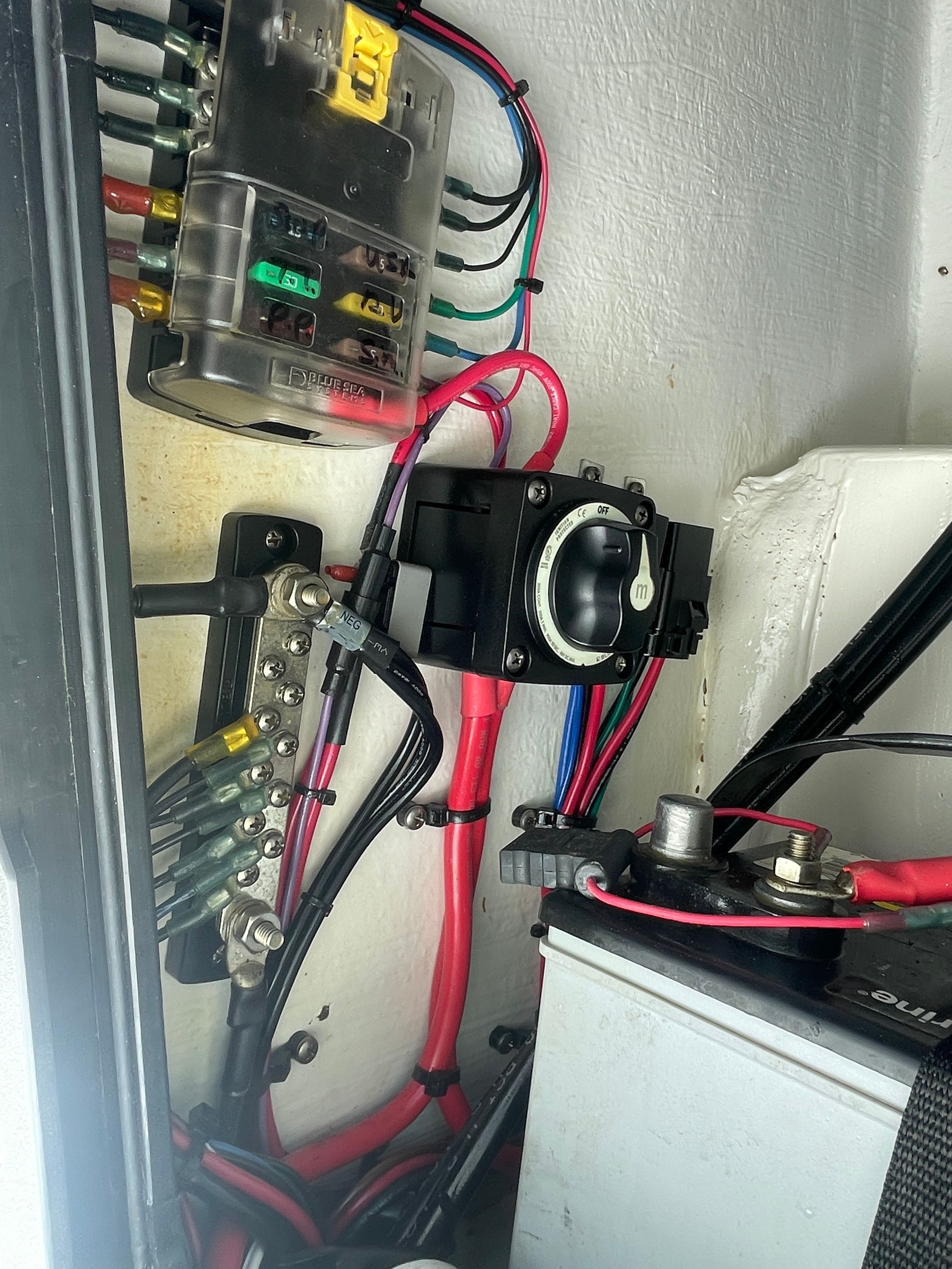 Electrical wiring and fuses inside a boat, featuring various cables and connections.