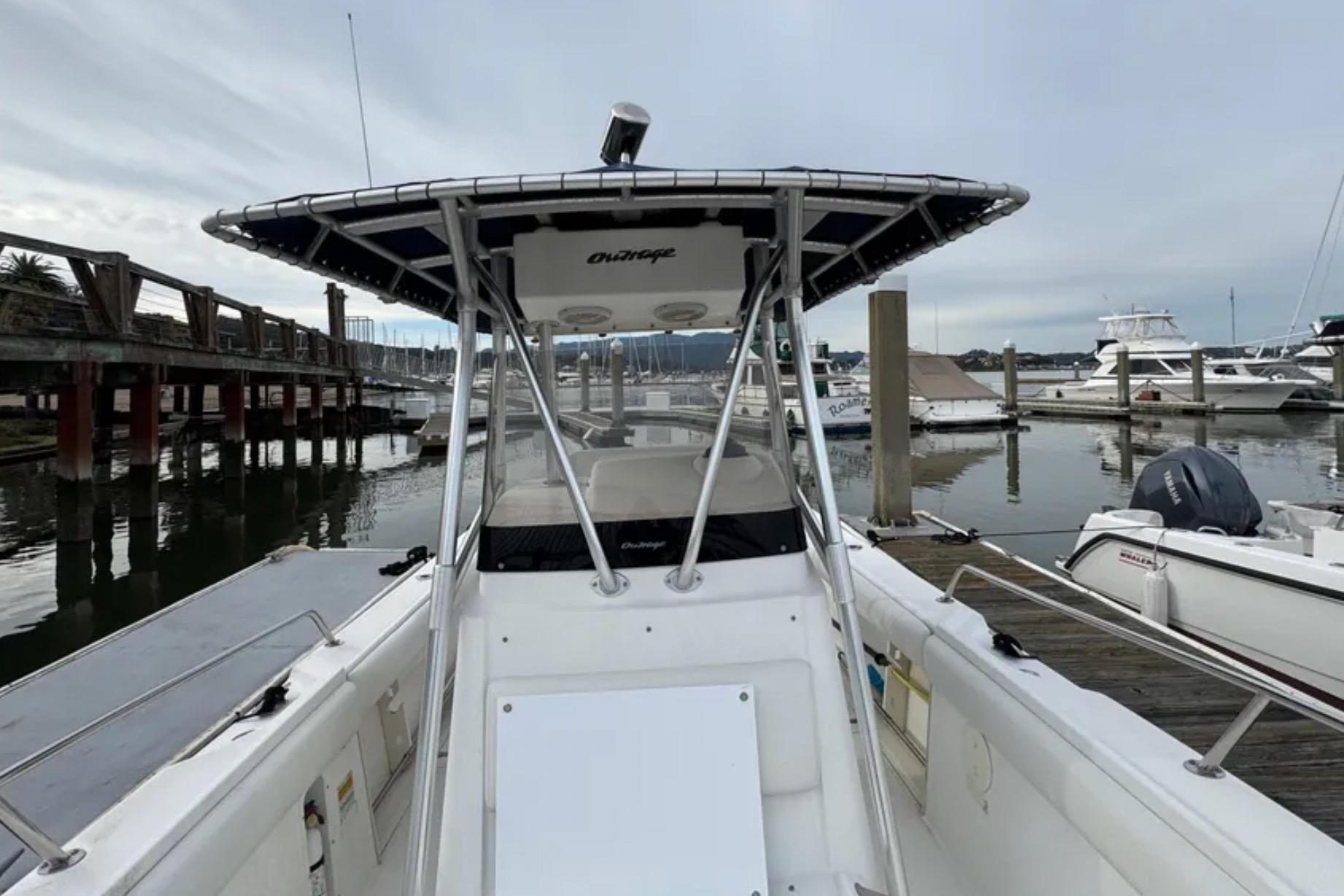 2001 Boston Whaler 26 Outrage boat docked at marina, featuring center console and T-top.