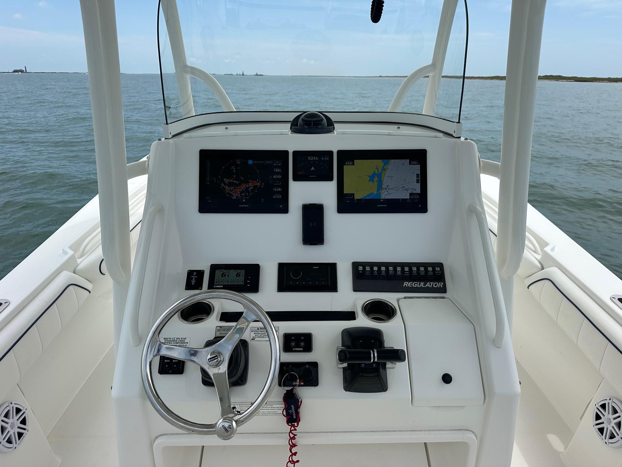 2016 Regulator center console boat dashboard with navigation screens and steering wheel on open water.