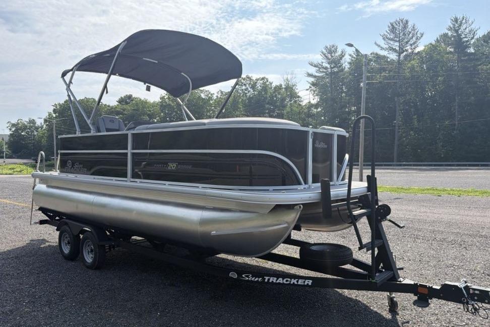 2026 Sun Tracker Party Barge 20 DLX pontoon boat on trailer, parked outdoors.