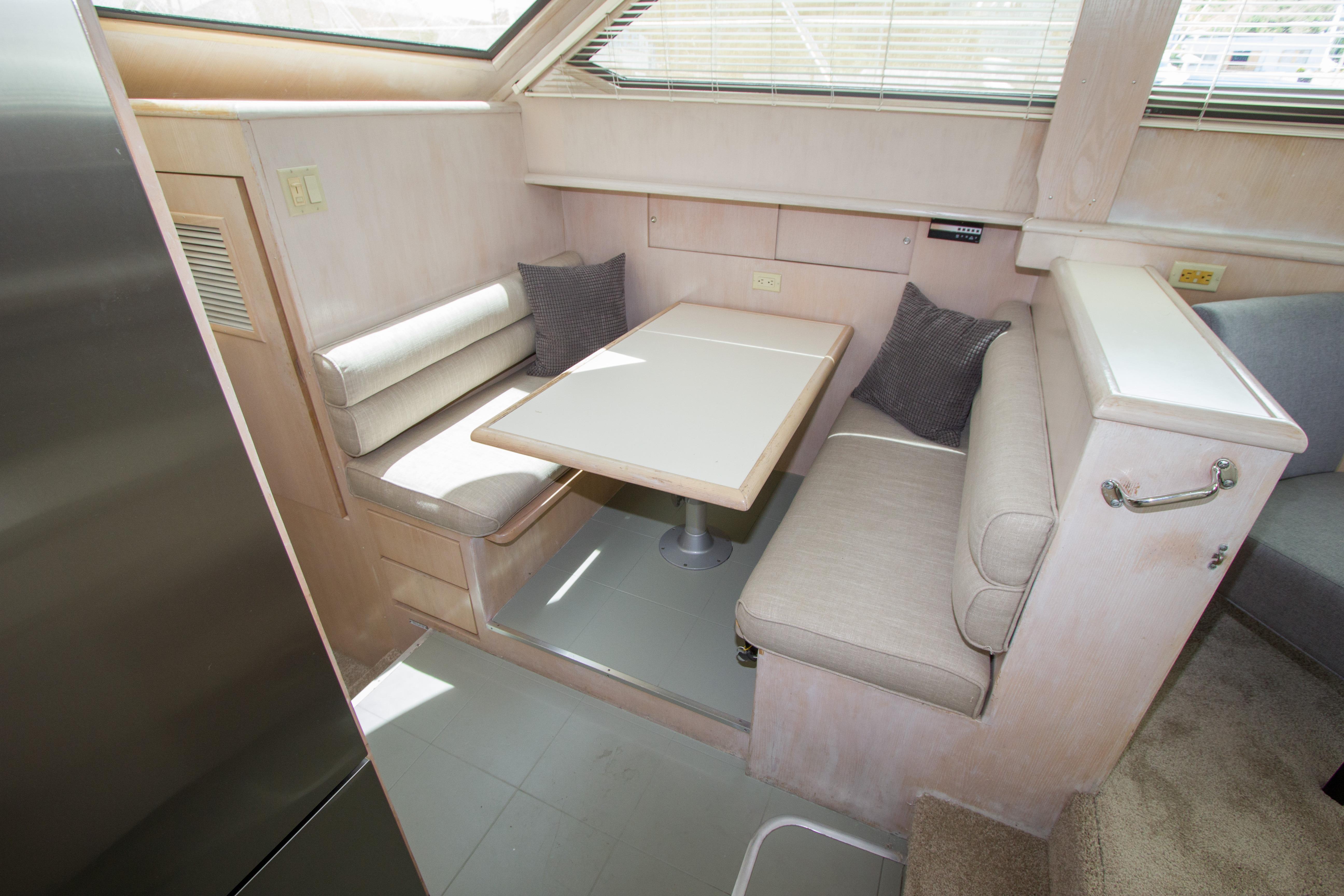 Interior of 1994 Hatteras 52 Cockpit Motor Yacht with cozy dining area and cushioned seating.