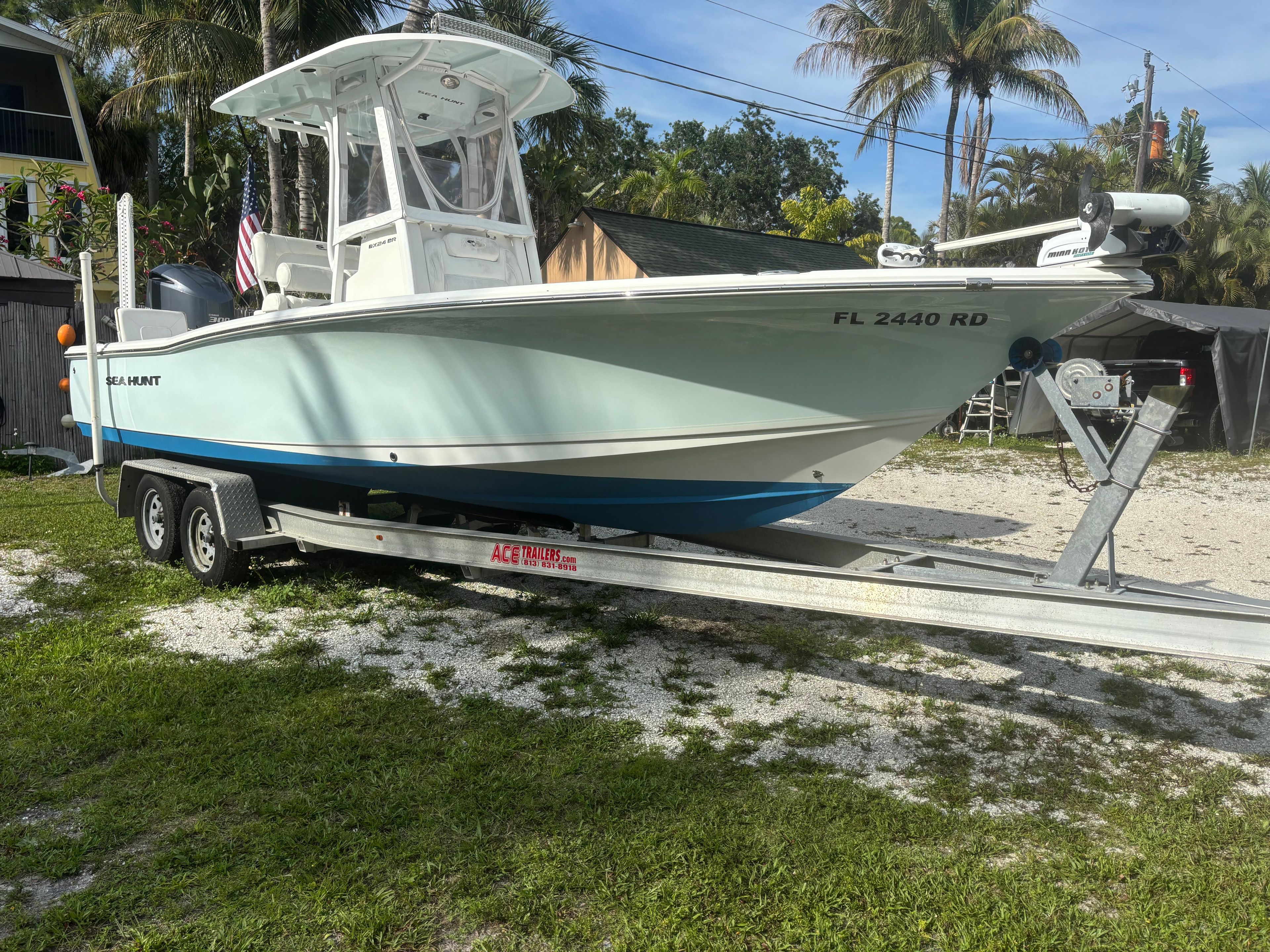 A 2016 Sea Hunt BX 24 BR boat on a trailer, surrounded by palm trees.