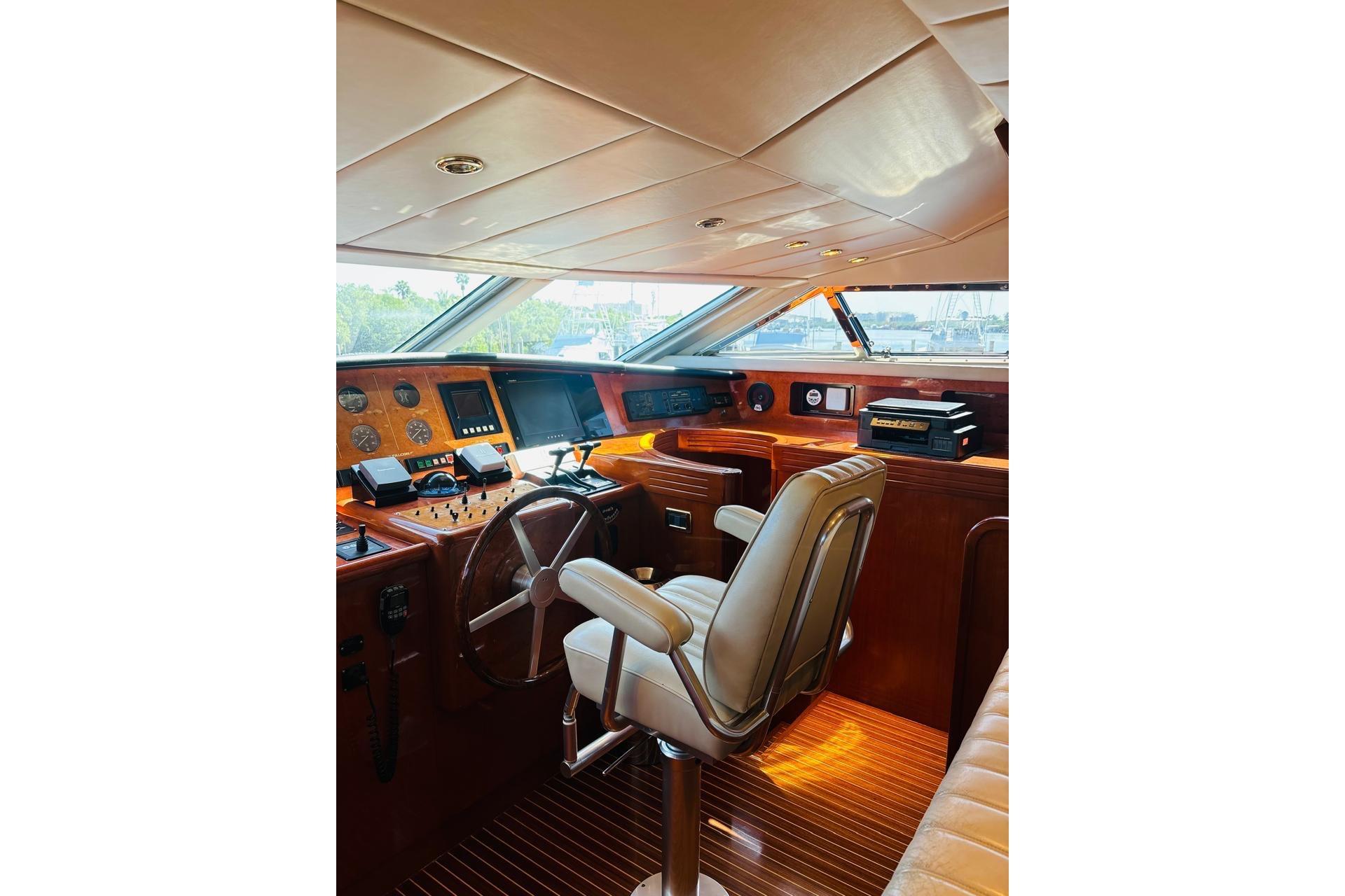 Luxurious interior of a 2000 Falcon 100 yacht cockpit with wooden accents and navigation equipment.