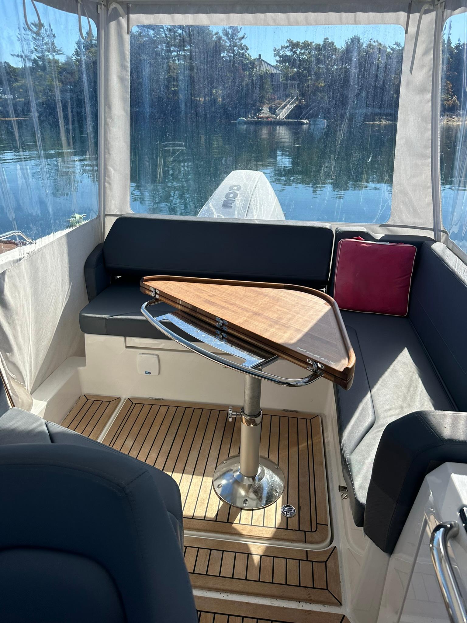 Interior of 2021 Nimbus W9 boat with wooden table and cushioned seating.