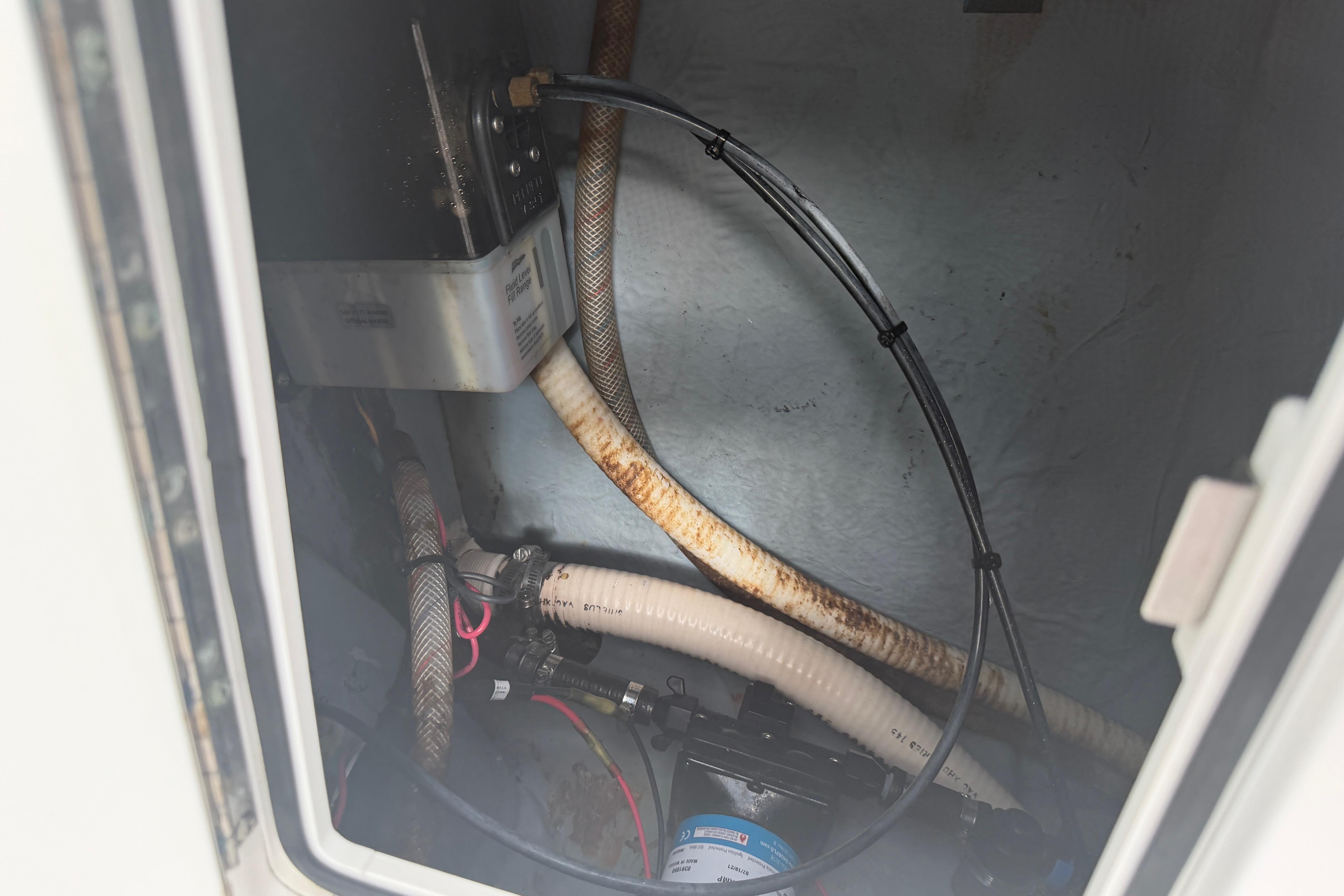 Interior view of a 1990 Mako 241 Center Console boat's compartment with hoses and wiring.