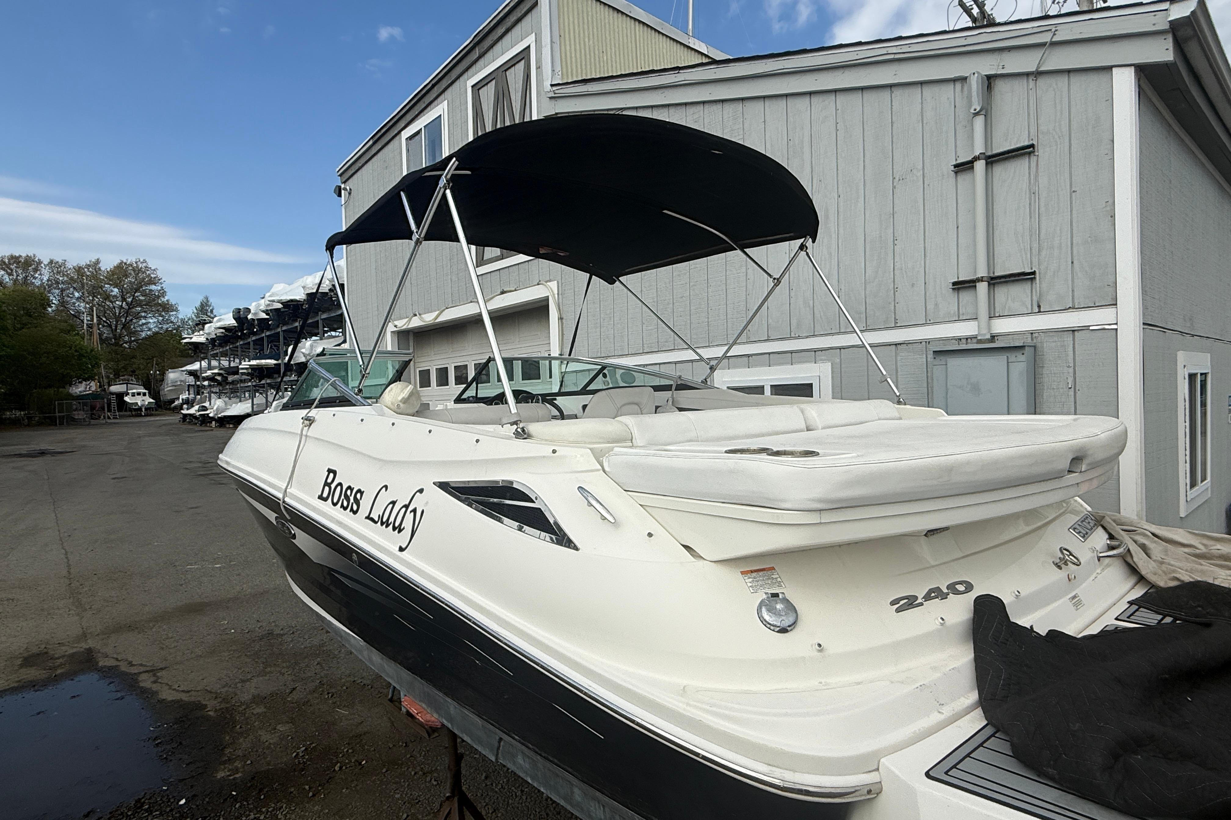 2015 Sea Ray 240 Sundeck boat with canopy, docked near a building.