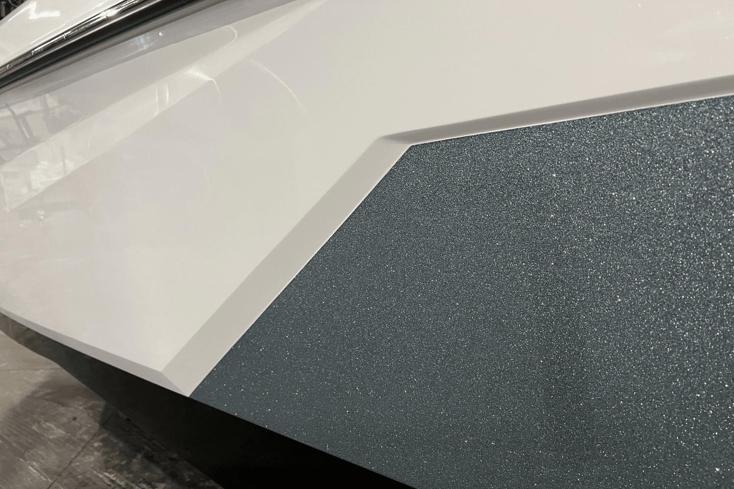 Close-up of 2023 Nautique Super Air Nautique S25 boat's sleek, textured exterior design.