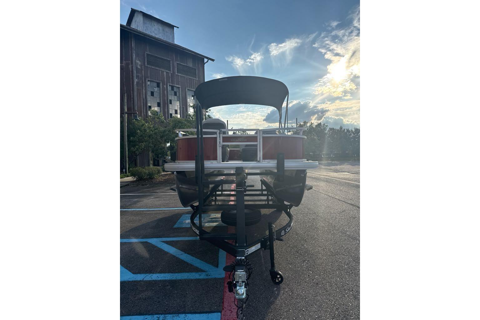 2026 Sun Tracker Bass Buggy 16 XL Select pontoon boat in parking lot, sunny day.