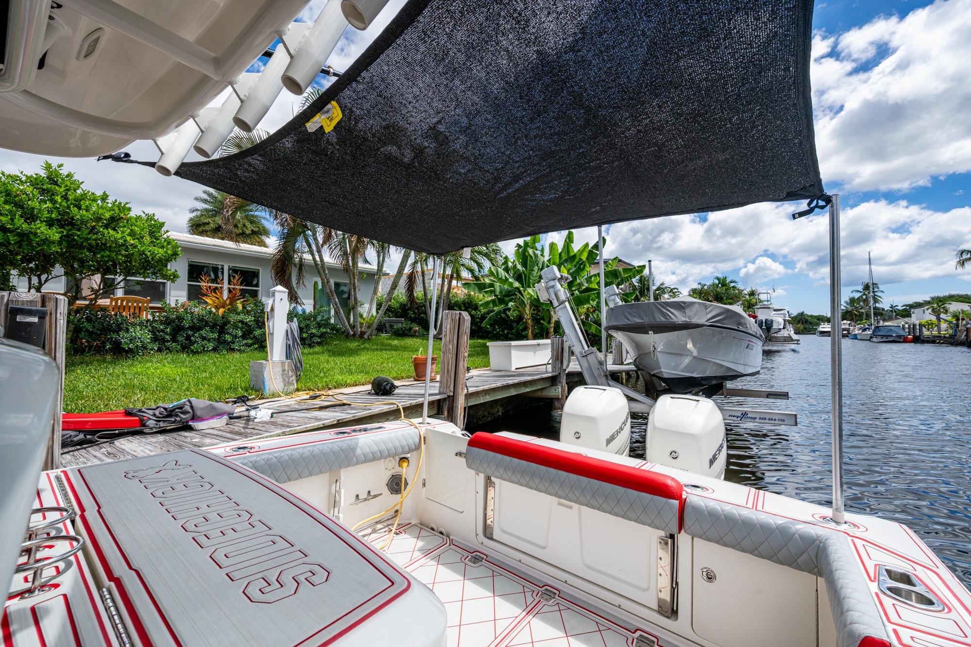 2018 Boston Whaler 330 boat docked, featuring shaded seating and twin engines.