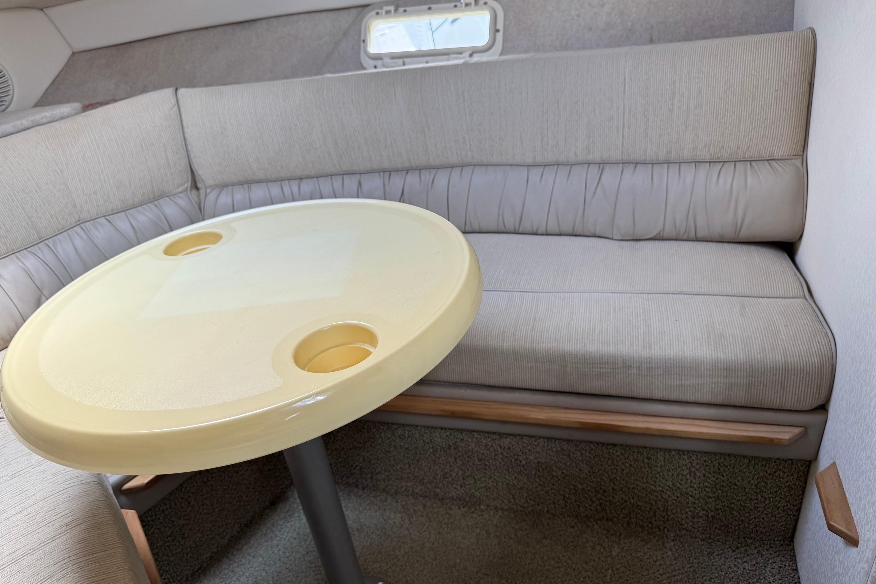 Interior of a 2000 Maxum 2400 SCR boat with cushioned seating and a round table.