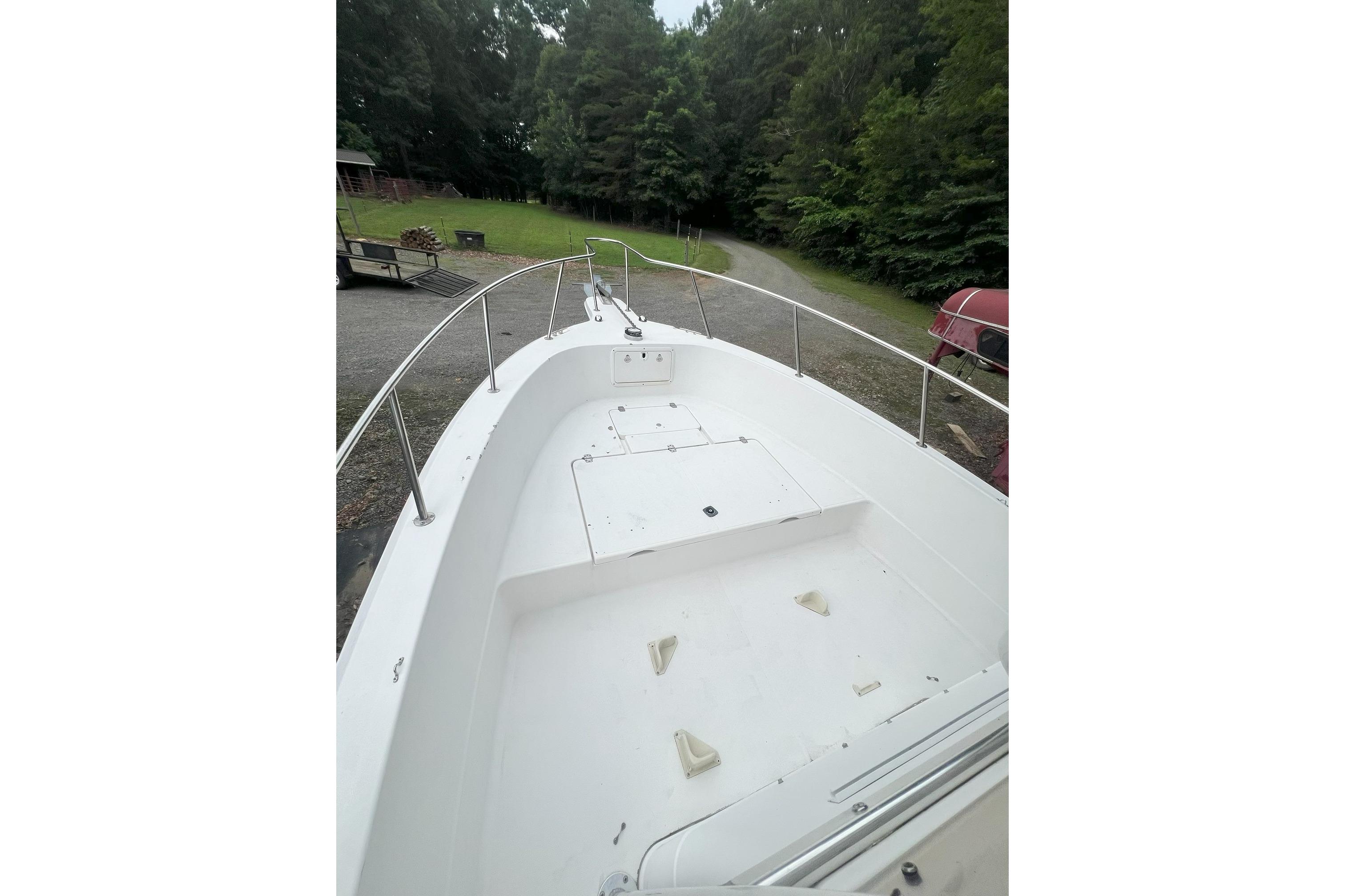 2000 Sport-Craft 240 Center Console boat, white deck, surrounded by lush greenery.