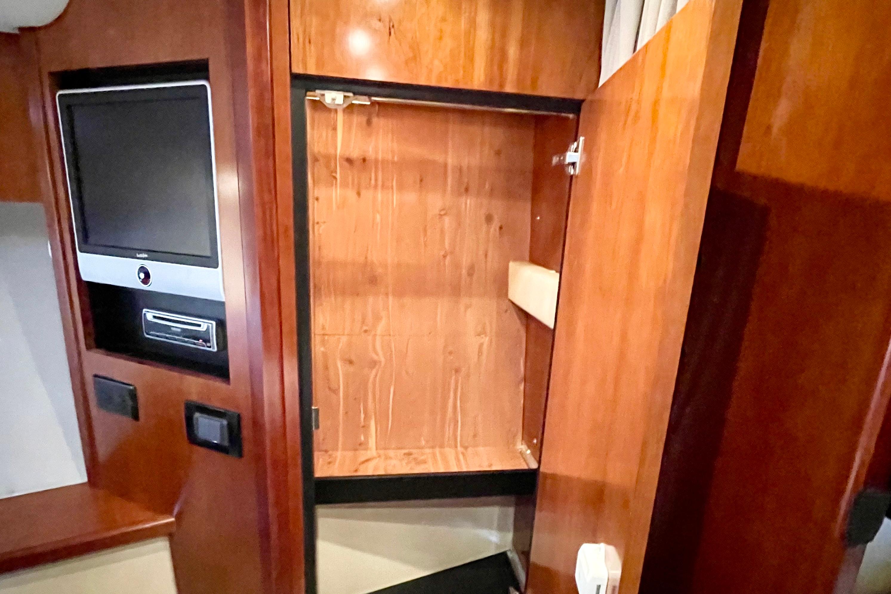 Interior of 2011 Cruisers Yachts 390 Sports Coupe with TV and open wooden cabinet.