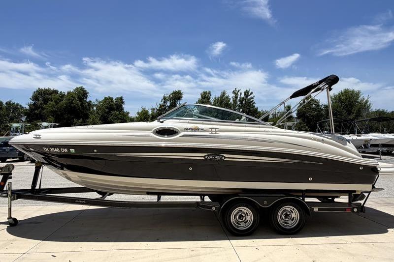 2007 Sea Ray 240 Sundeck boat on trailer, parked outdoors under a clear blue sky.