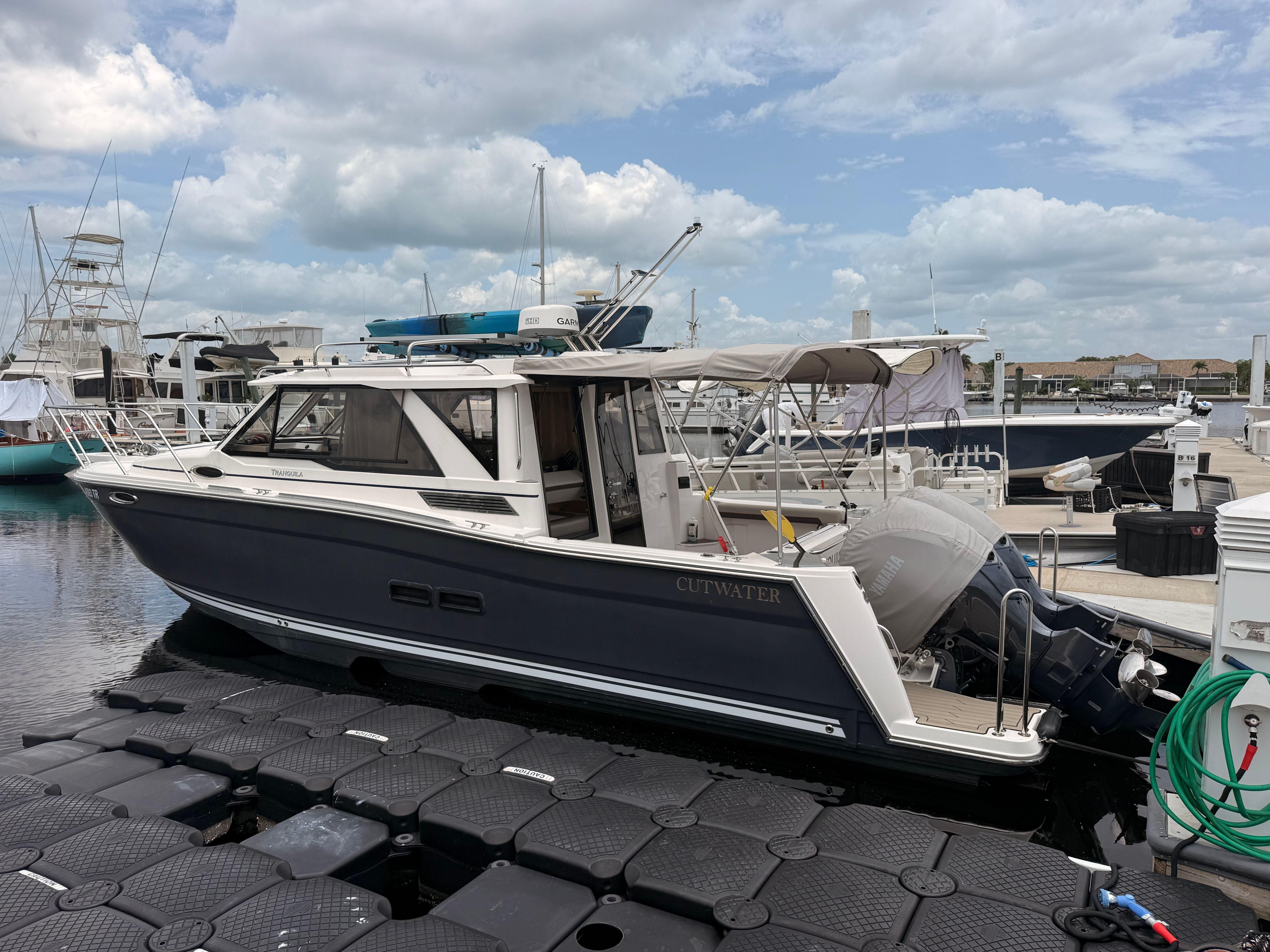 A 2023 Cutwater C-228 docked at a marina. It features a sleek design and an outboard motor.