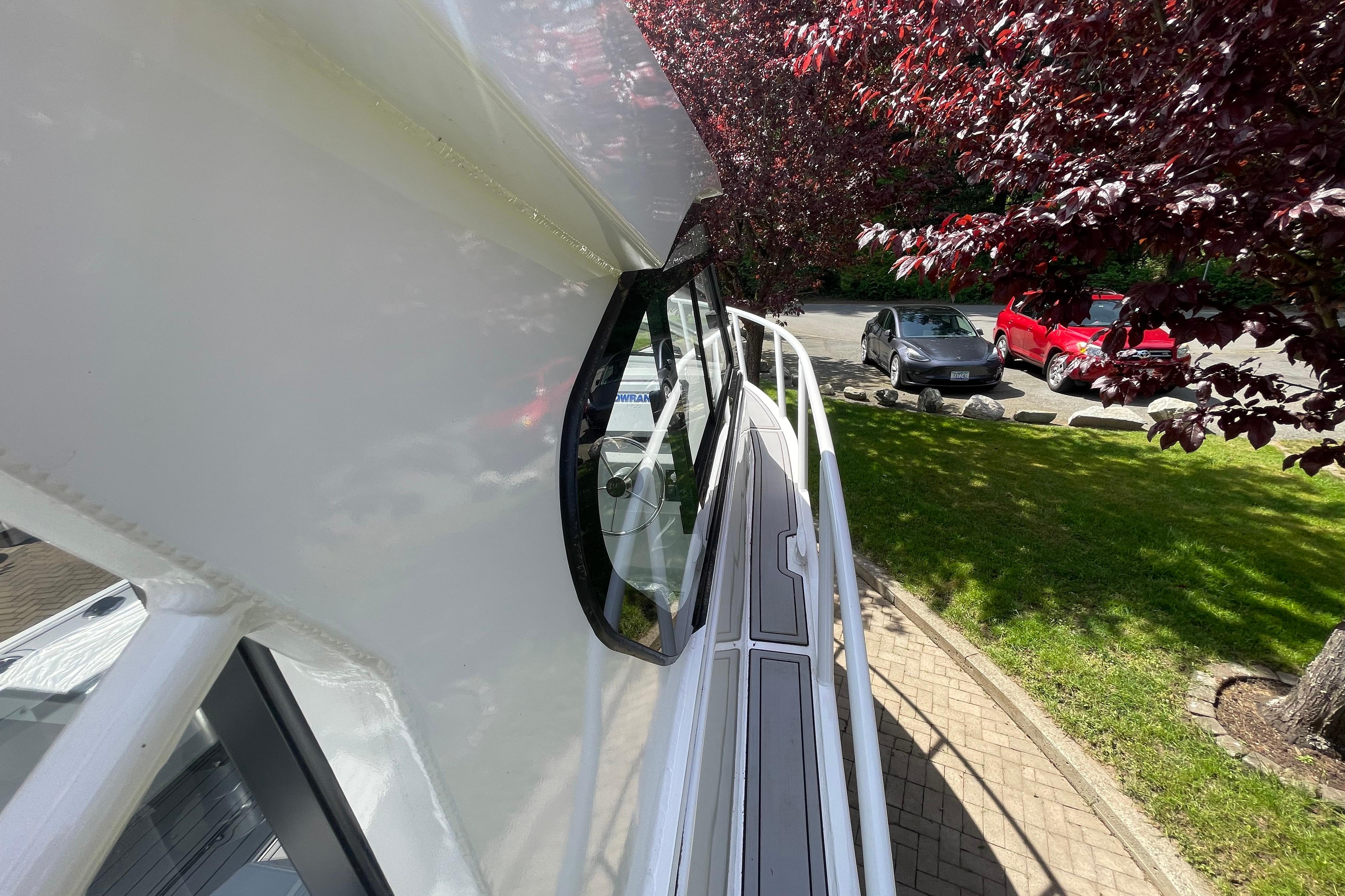 2025 Custom Aluminum 7.5 Profisher boat, side view, parked near trees and cars.