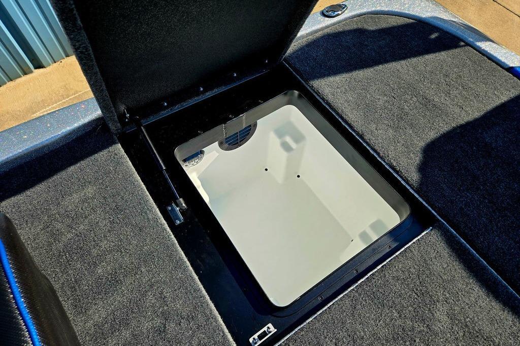 Open storage compartment in 2026 Skeeter ZXE20 boat, featuring carpeted interior.