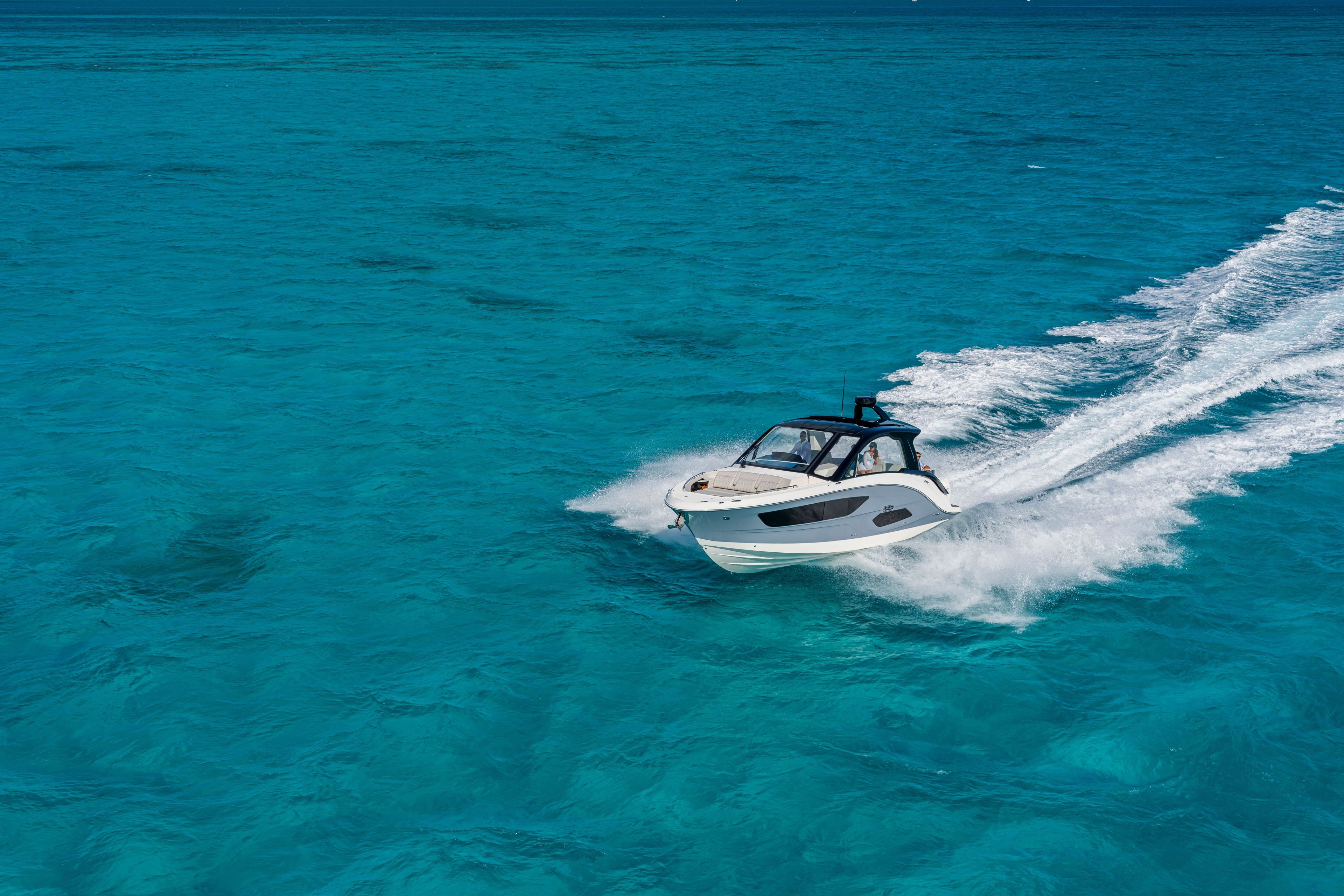 A 2026 Sea Ray Sundancer 370 Outboard speeds across clear, turquoise water.