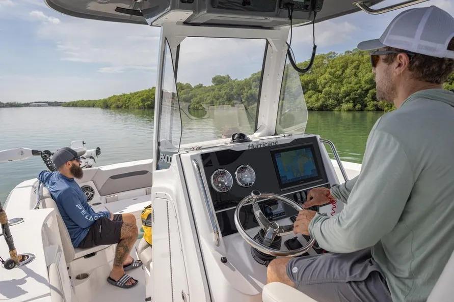 Two people on a 2025 Hurricane Center Console 24 OB boat navigating a calm waterway.